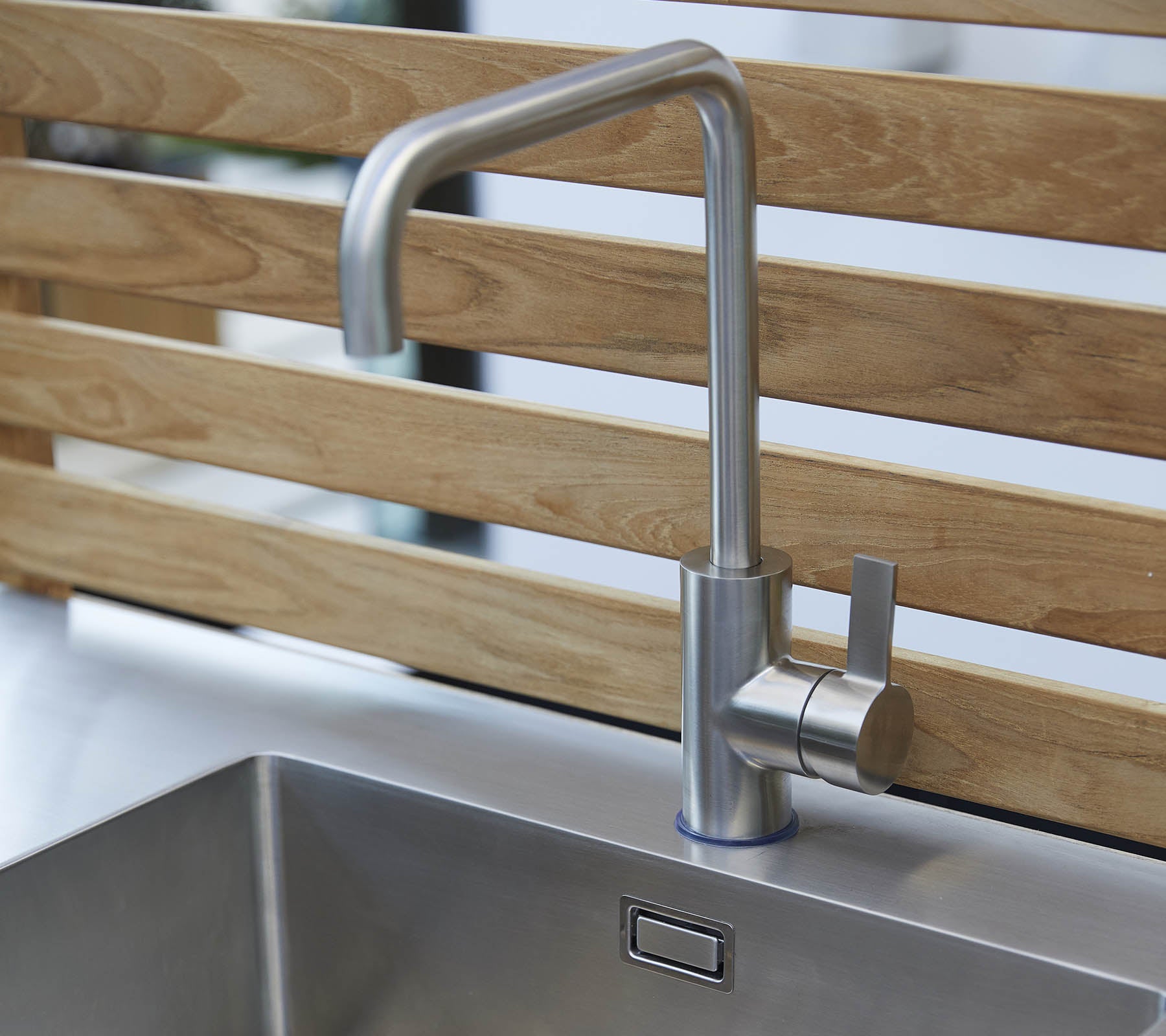 Grifo de acero inoxidable elegante con un diseño estilizado y un control de palanca única, ubicado sobre un fregadero moderno.