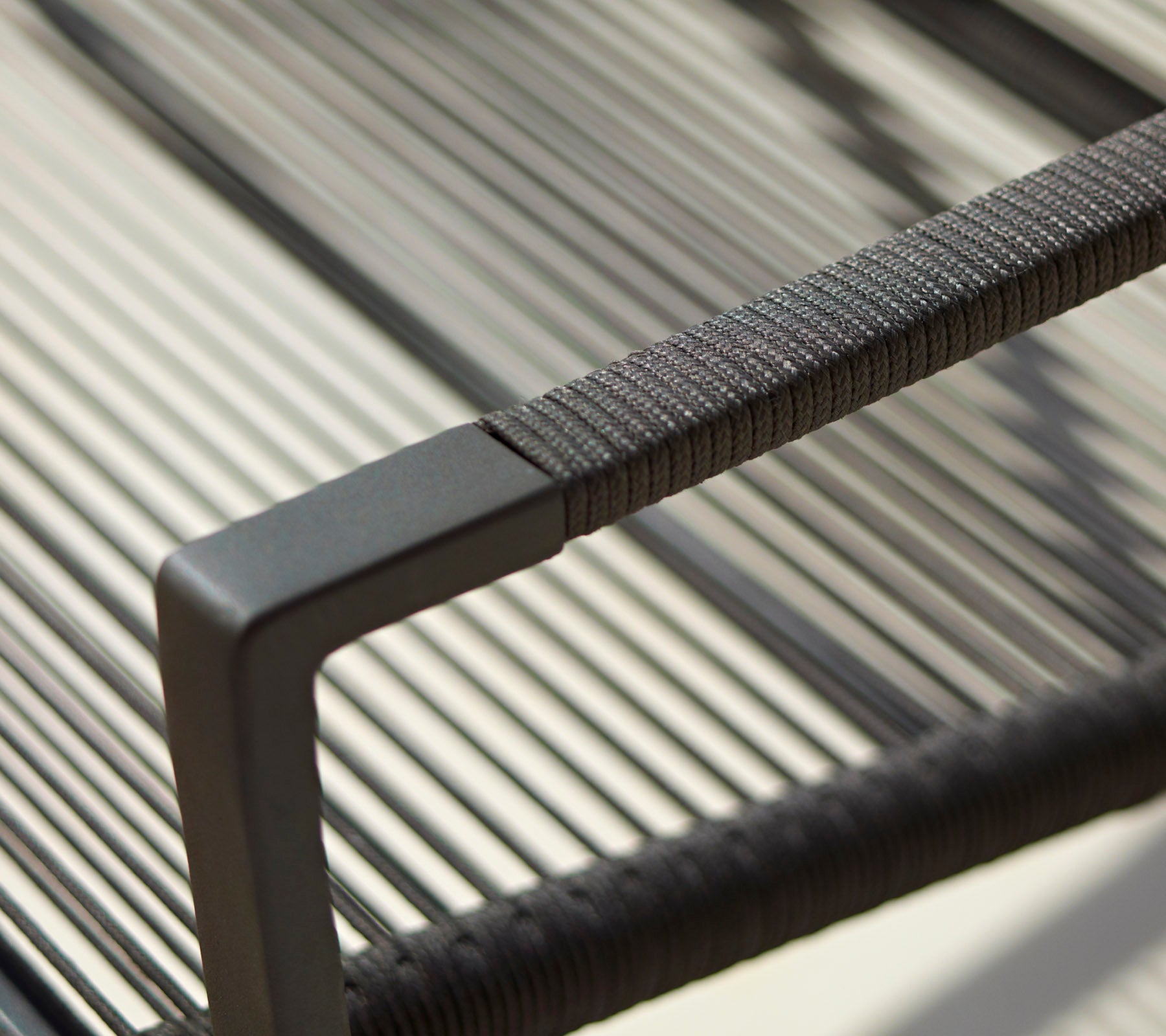 Primer plano del reposabrazos de una silla moderna con un diseño elegante, detalles texturizados y un acabado negro minimalista.