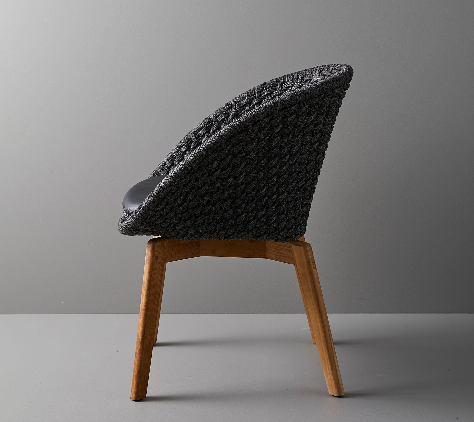 Silla elegante con respaldo tejido y patas de madera, que ofrece un diseño moderno ideal para espacios contemporáneos.