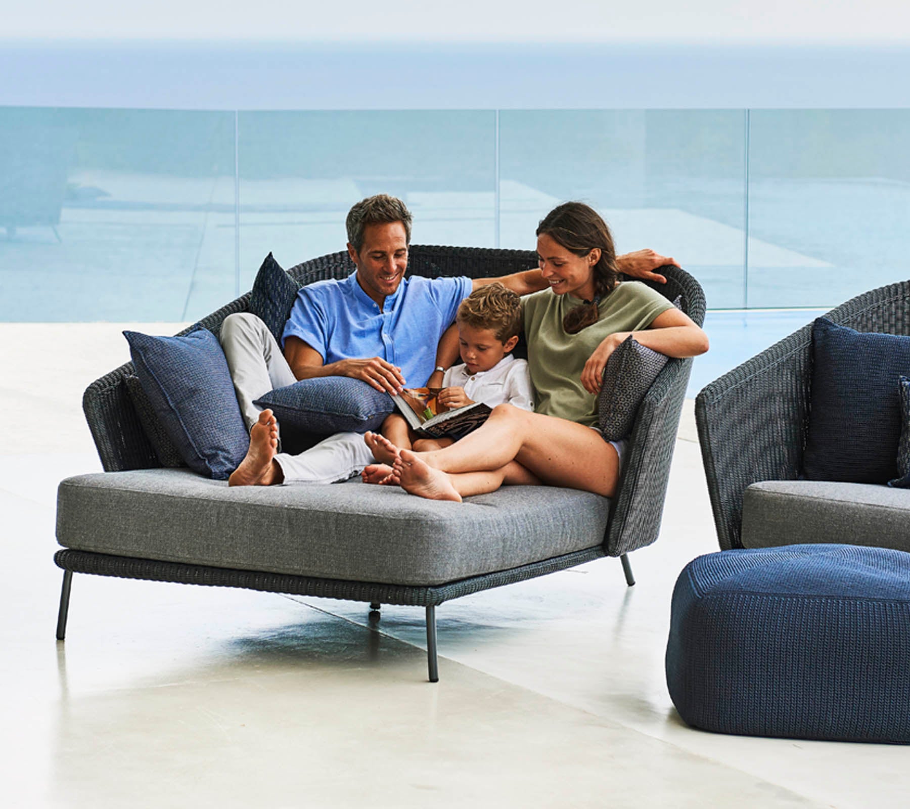 La familia disfruta de tiempo de calidad juntos, leyendo un libro en una silla lounge elegante y cómoda con suaves cojines.
