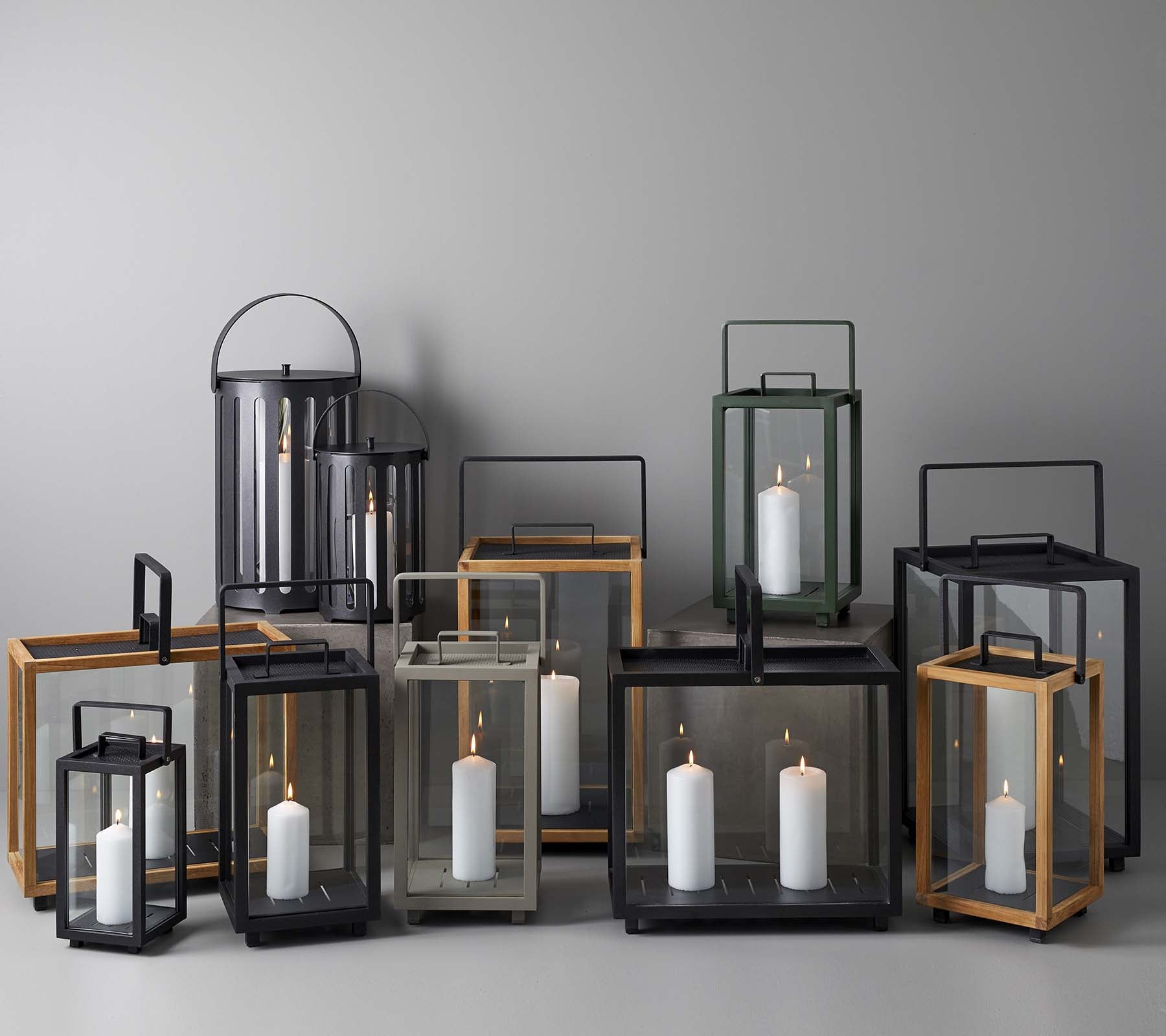 Una colección de elegantes faroles en varias tamaños y estilos, con velas en su interior, organizados juntos sobre un fondo neutro.