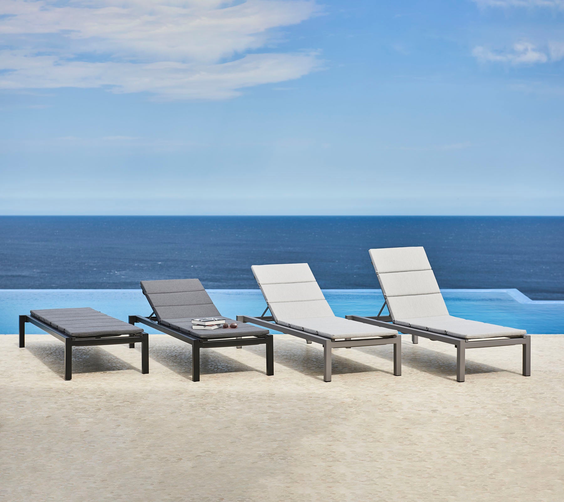 Cuatro sillones elegantes con un diseño aerodinámico, situados cerca de un sereno cuerpo de agua, creando un espacio de relajación tranquilo.