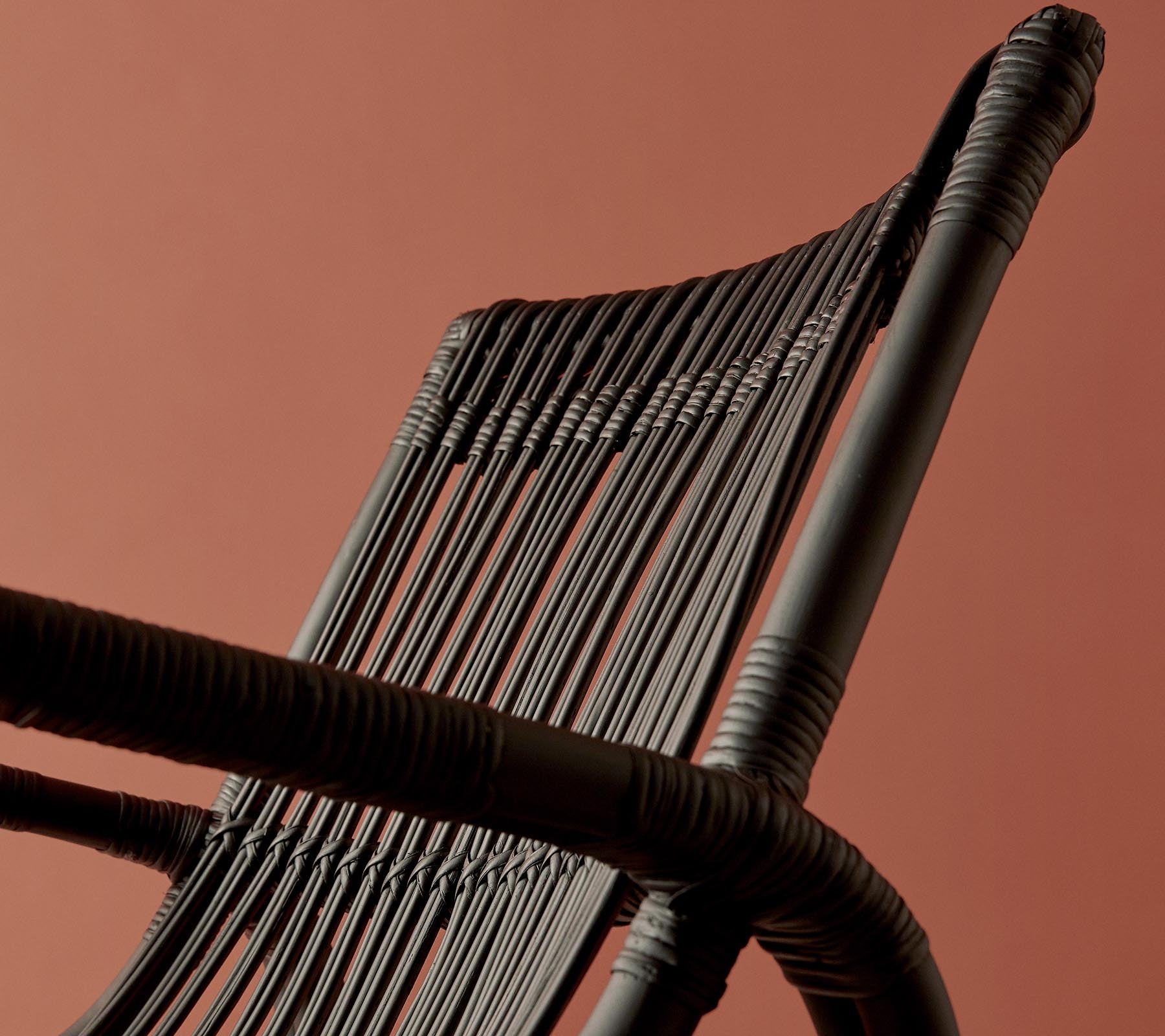 Una vista en primer plano de un respaldo de silla tejido contra un fondo de color cálido, que destaca su diseño y textura intrincados.