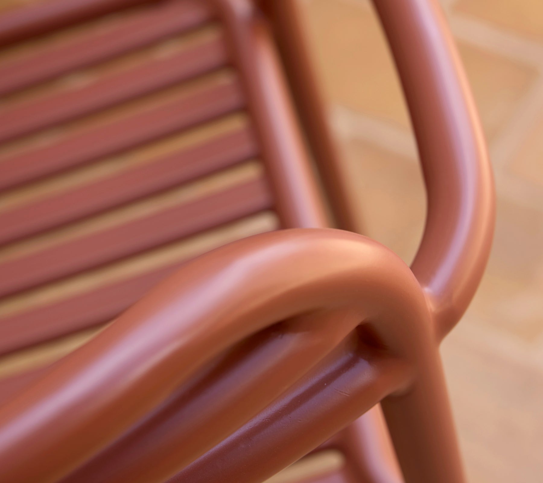 Primer plano de una silla Bliss en un tono rojo desértico, mostrando sus suaves curvas y diseño de listones.