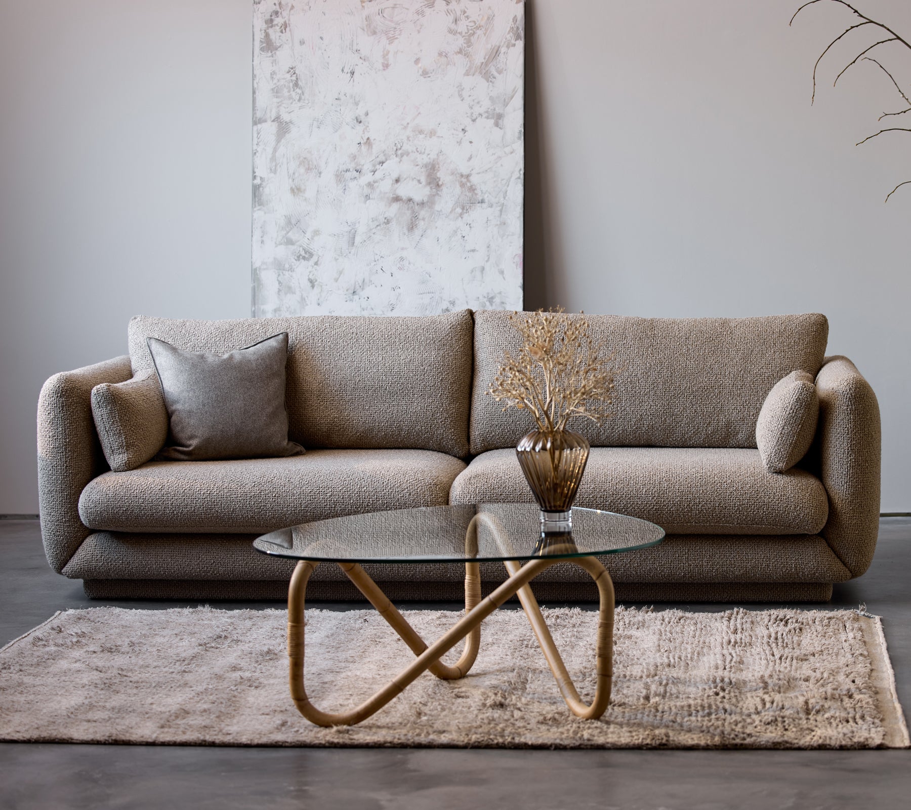 Sofá Bloom de 3 plazas en taupe flair con un zócalo, combinado con una mesa de café Wave y un jarrón decorativo, sobre una suave alfombra.