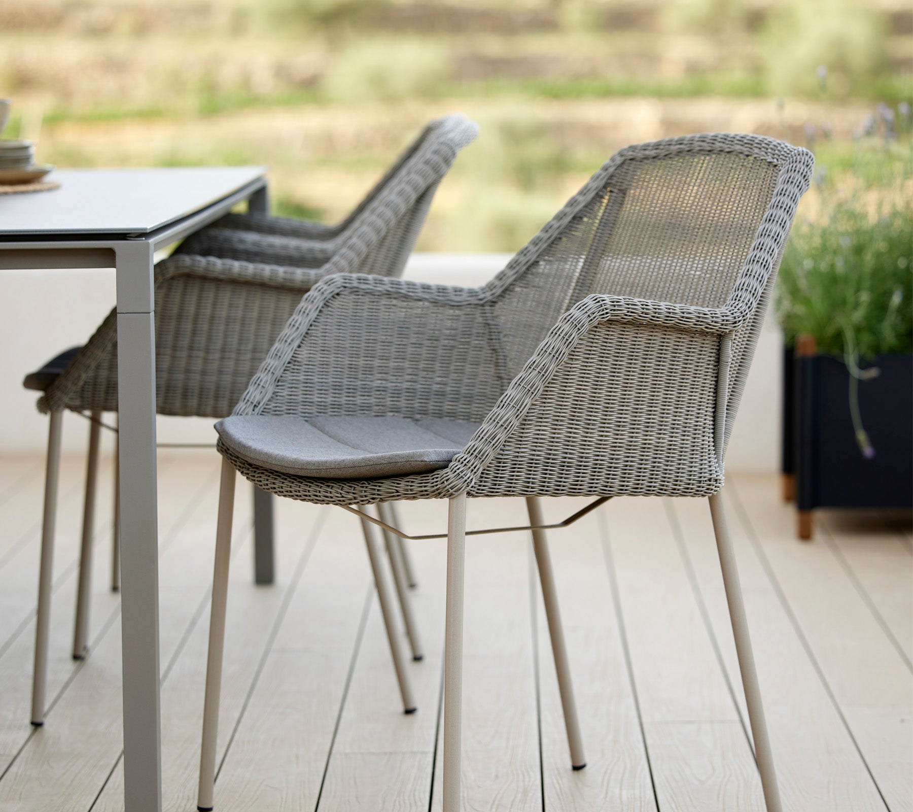 Dos sillas tejidas elegantes al lado de una mesa moderna, con un diseño elegante y cojines cómodos, ideales para relajarse en un entorno sereno.