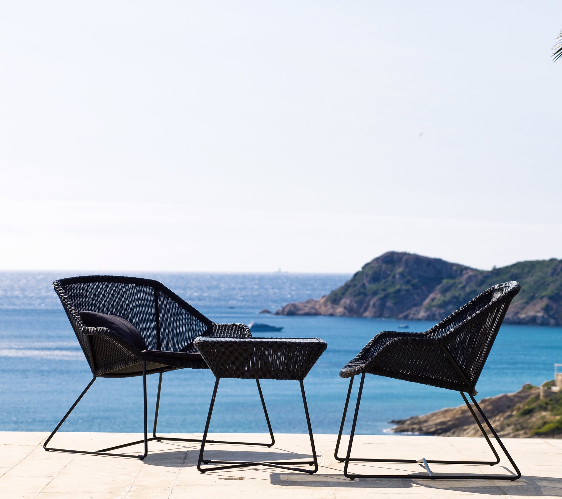 Dos sillas negras y una mesa negra con vista al mar.