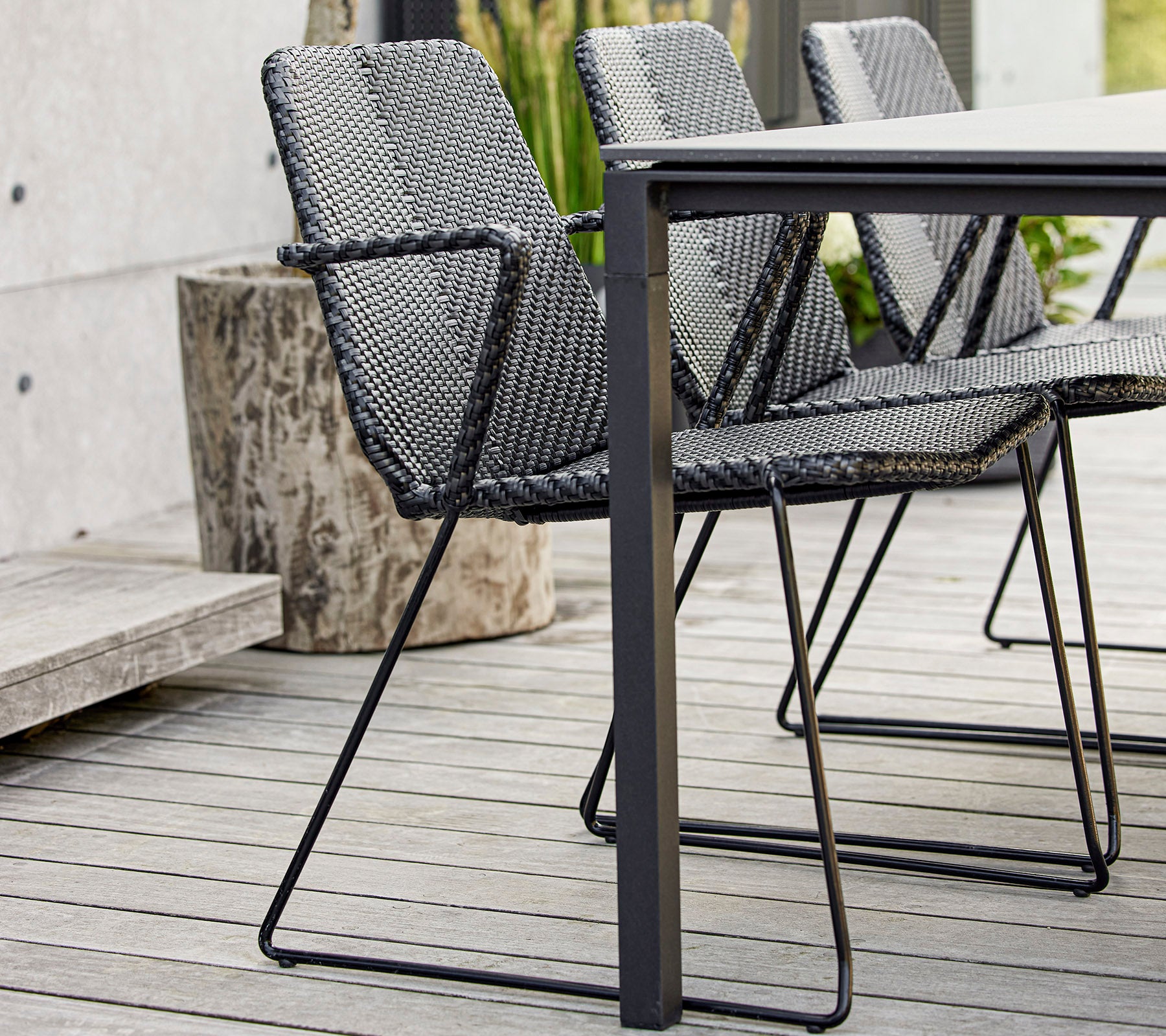 Un conjunto de modernas sillas negras tejidas situadas alrededor de una mesa elegante, que muestra un diseño contemporáneo y artesanía.