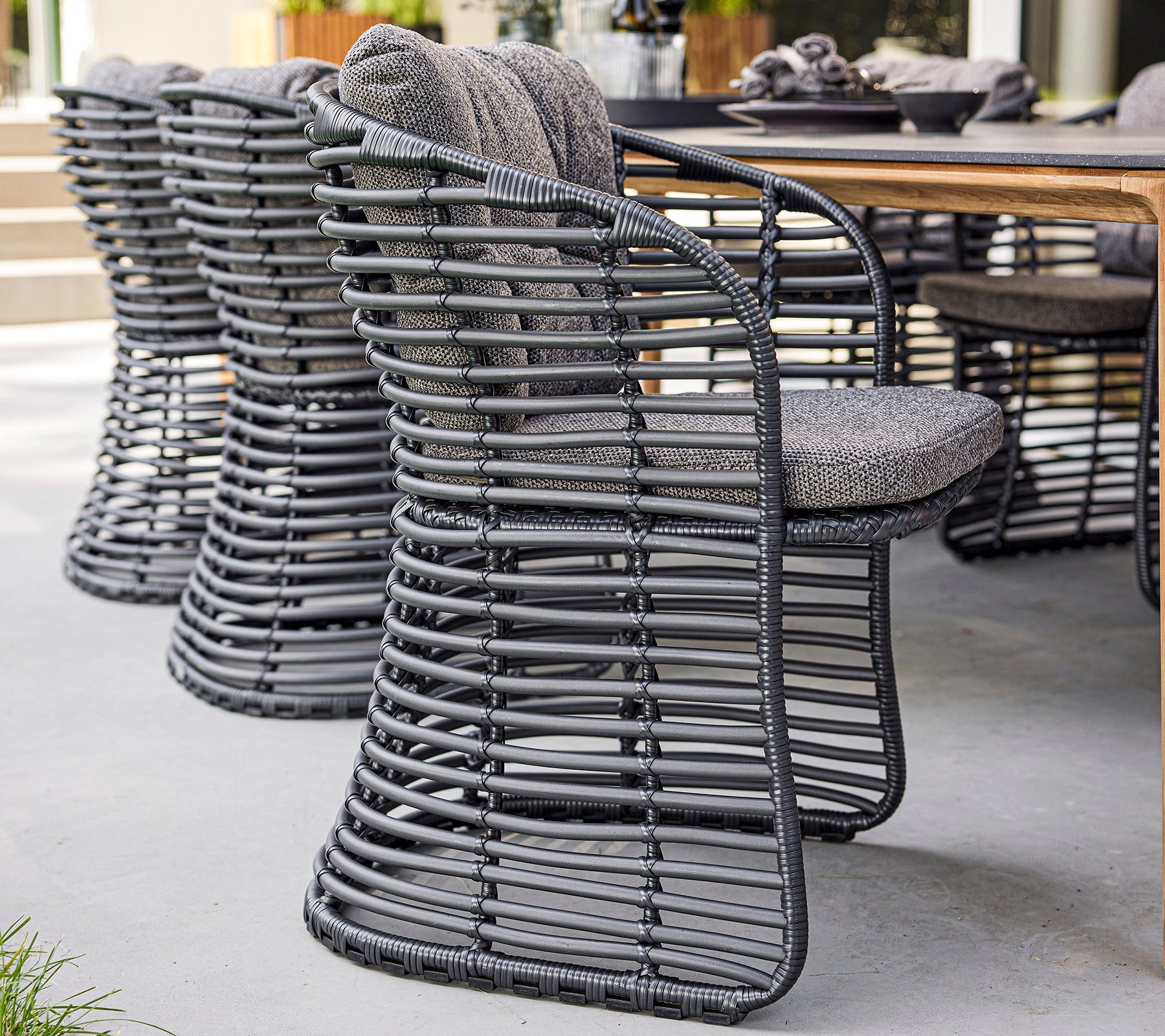 Sillas tejidas elegantes con un diseño moderno y asientos acolchados, dispuestas al lado de una mesa de madera.