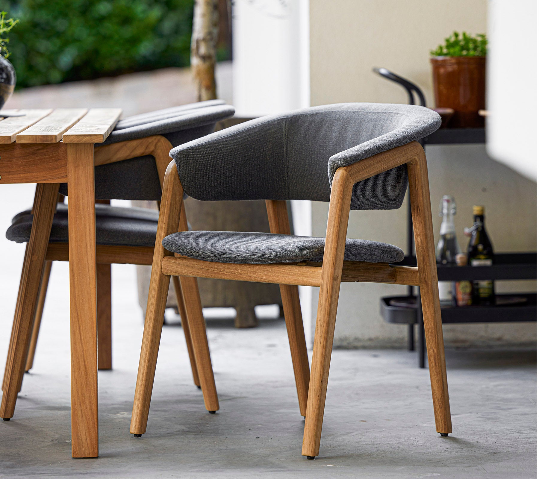 Silla elegante con estructura de madera y tapizado gris, diseñada para la comodidad y la elegancia, perfecta para entornos modernos.