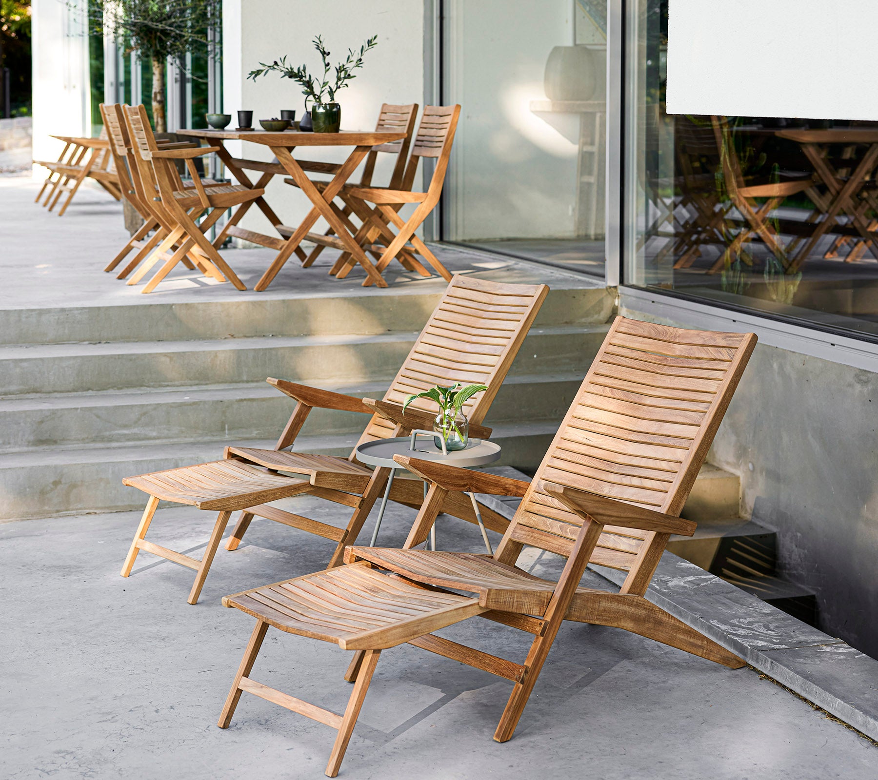 Conjunto de muebles de madera elegante con sillas reclinables, una mesa auxiliar y una mesa de comedor, perfecto para reuniones acogedoras y relajación.