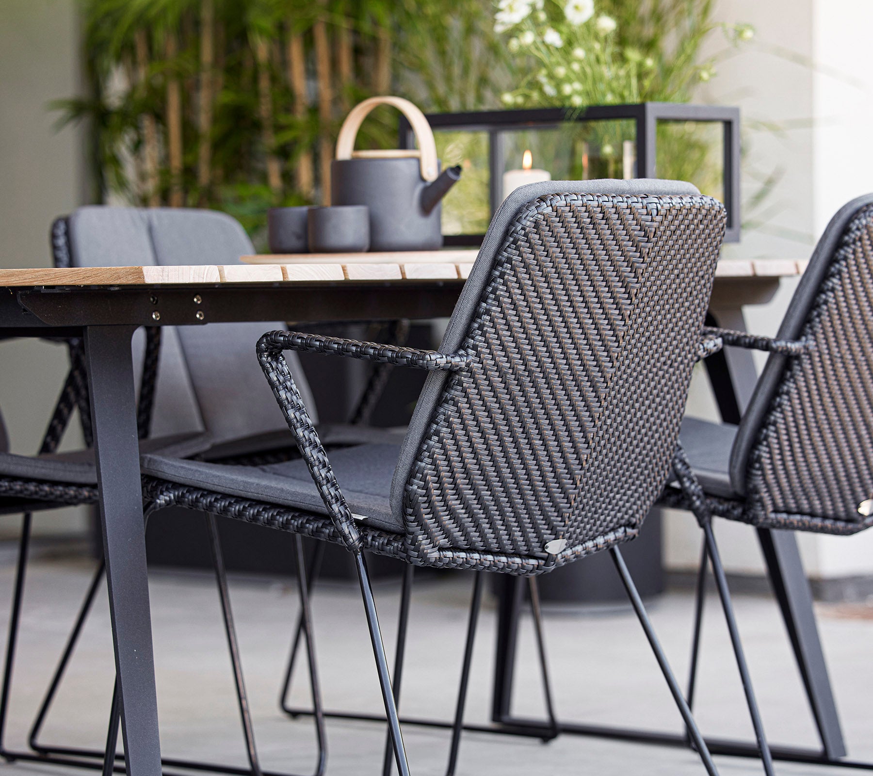 Asientos contemporáneos con sillas de mimbre grises alrededor de una mesa de madera, complementados con elementos decorativos en una disposición elegante.