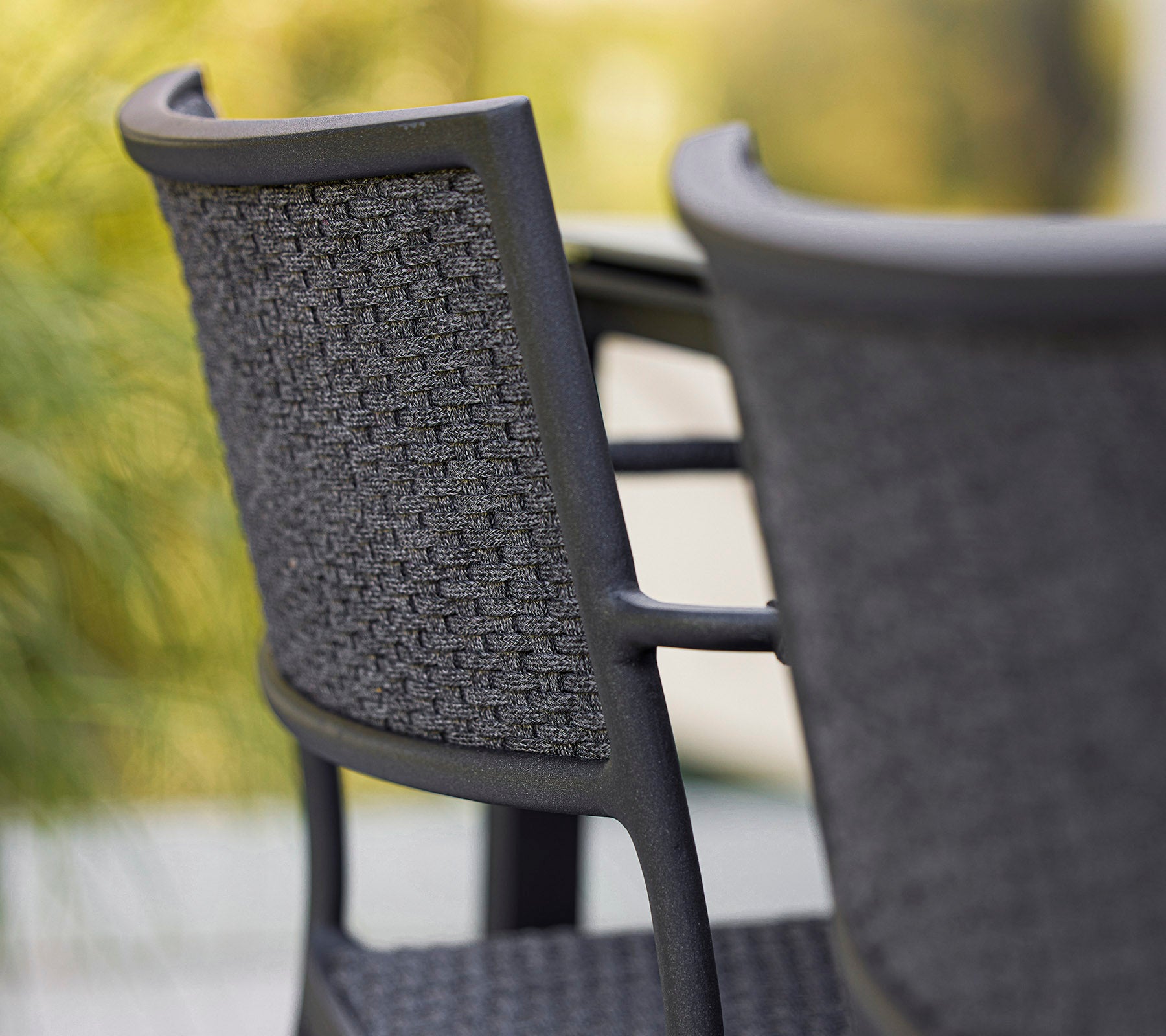 Primer plano de una silla elegante con un respaldo tejido, que muestra un diseño moderno en tonos de gris. Perfecta para espacios contemporáneos.