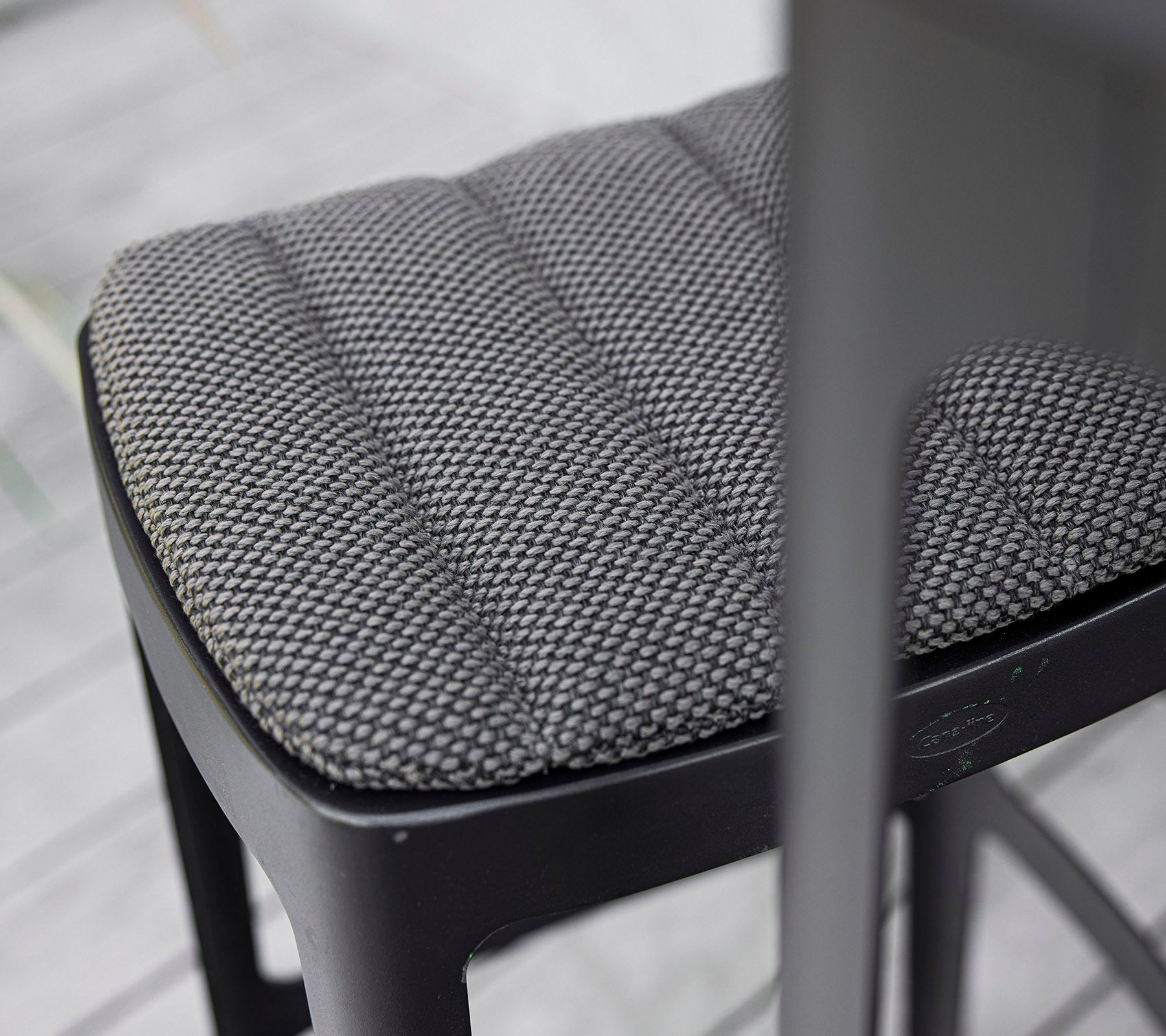 Primer plano de un asiento de silla negro texturizado con un diseño acolchado, que muestra la artesanía moderna y la atención al detalle.