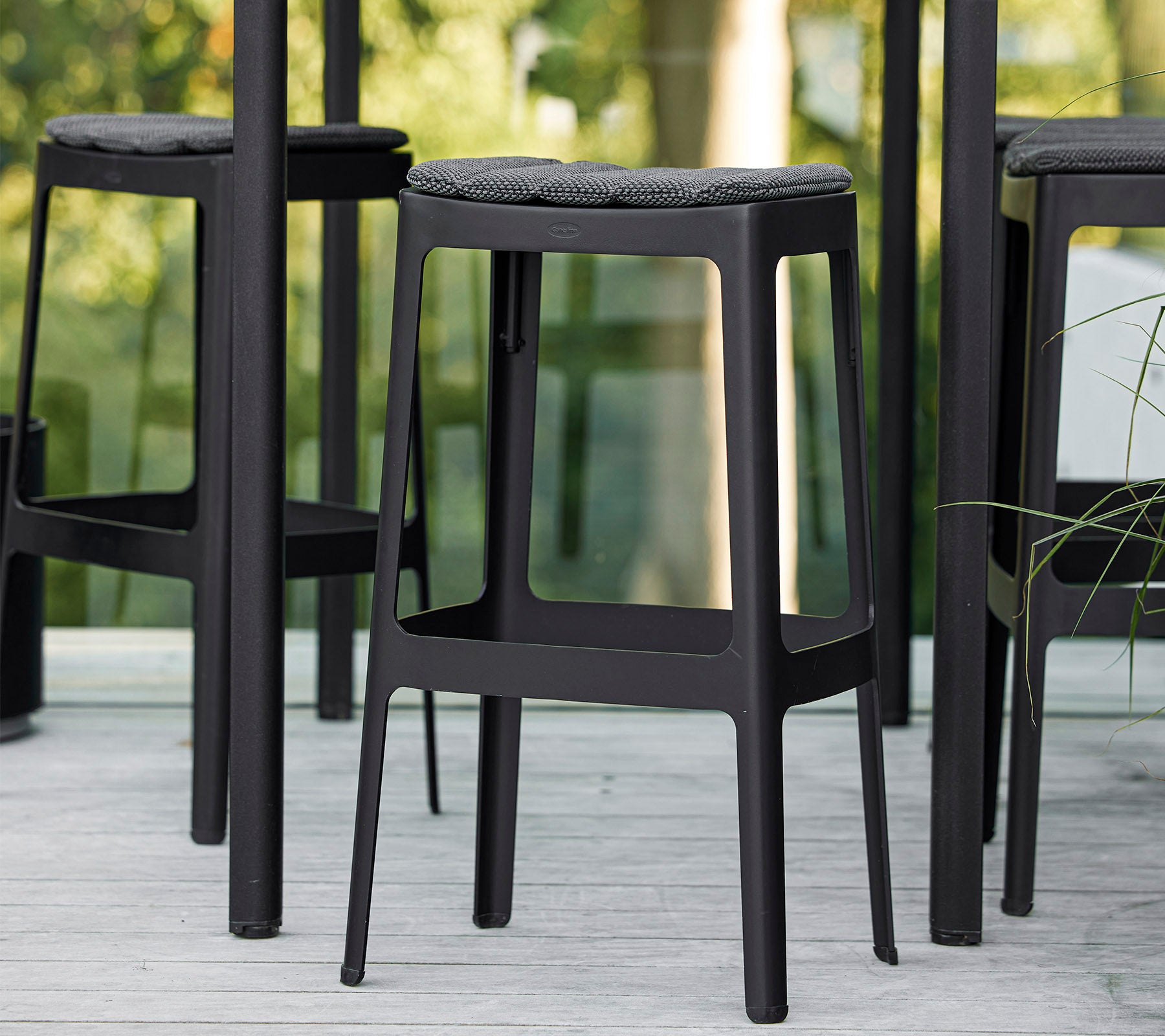 Taburetes de bar negros con un diseño minimalista y asientos acolchados, dispuestos muy juntos, mostrando una estética moderna.