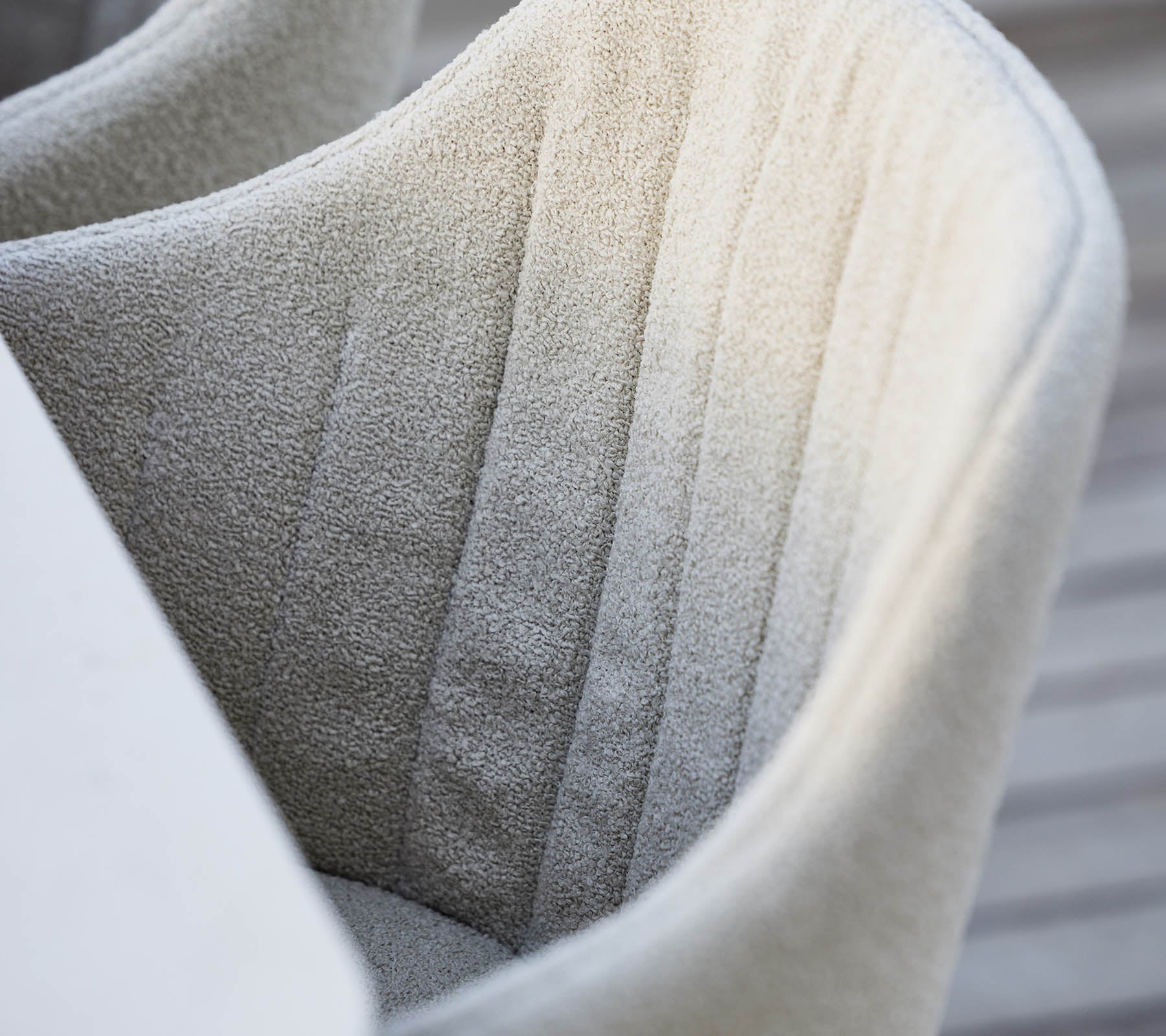Silla texturizada completamente tapizada con suturas verticales sutiles, que muestra un color suave y neutro y una estética de diseño moderna.