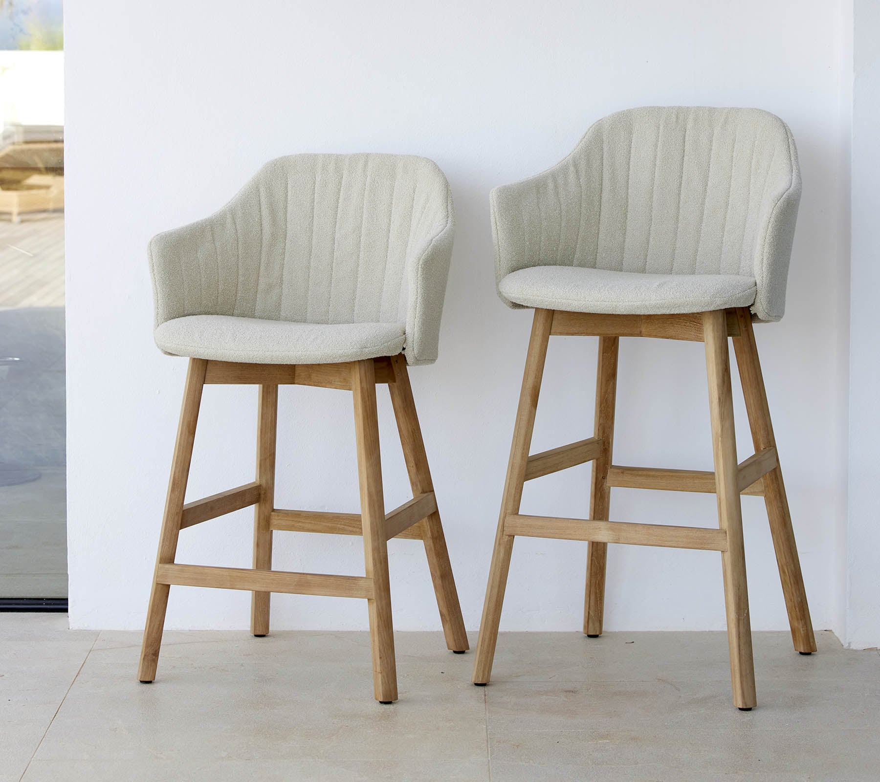 Dos sillas elegantes de color claro con respaldos curvados y patas de madera, que muestran un diseño moderno y cómodo.
