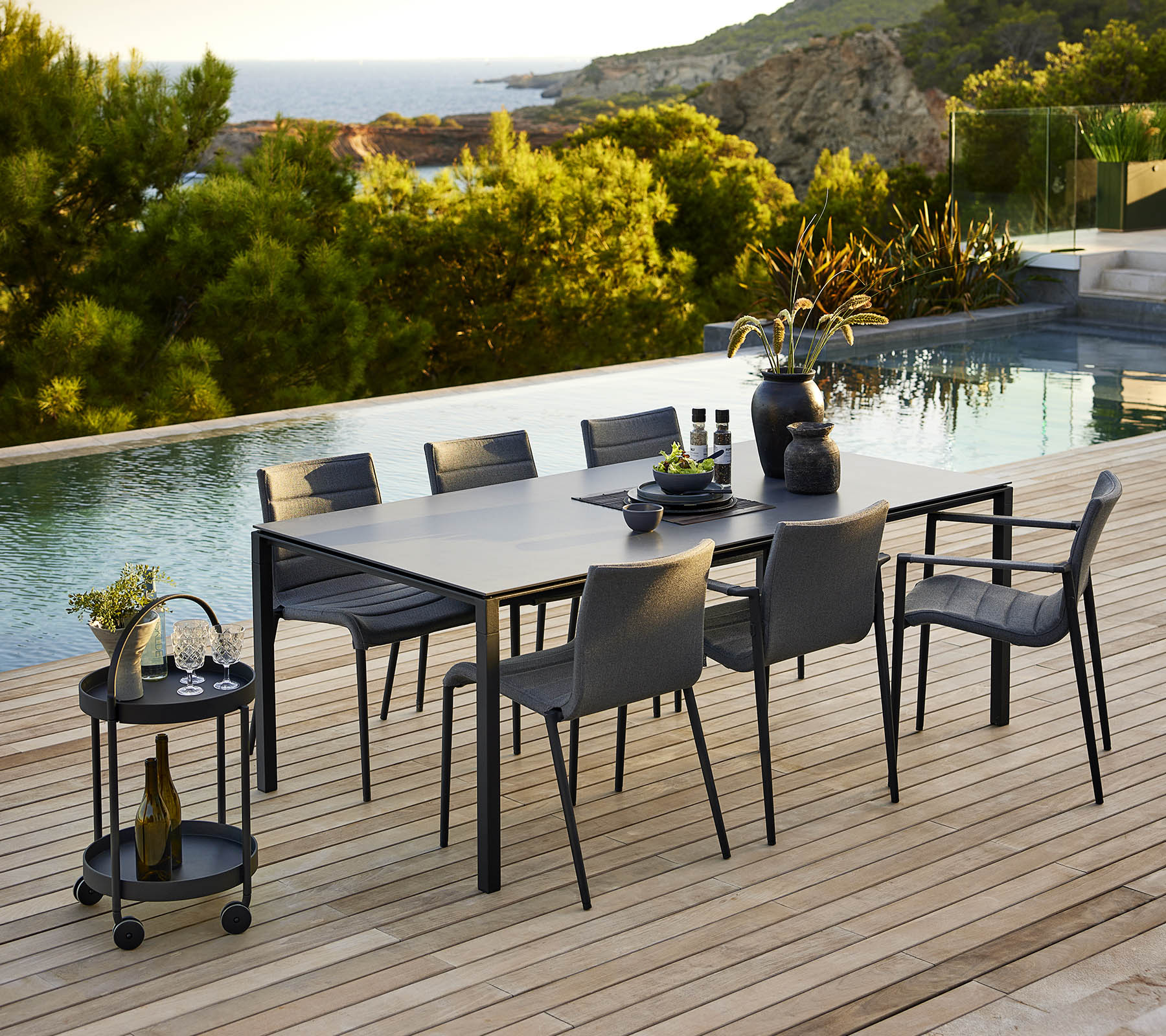 Configuración de comedor elegante con una mesa elegante y sillas a juego, complementada con accesorios decorativos y un tranquilo telón de fondo al aire libre.