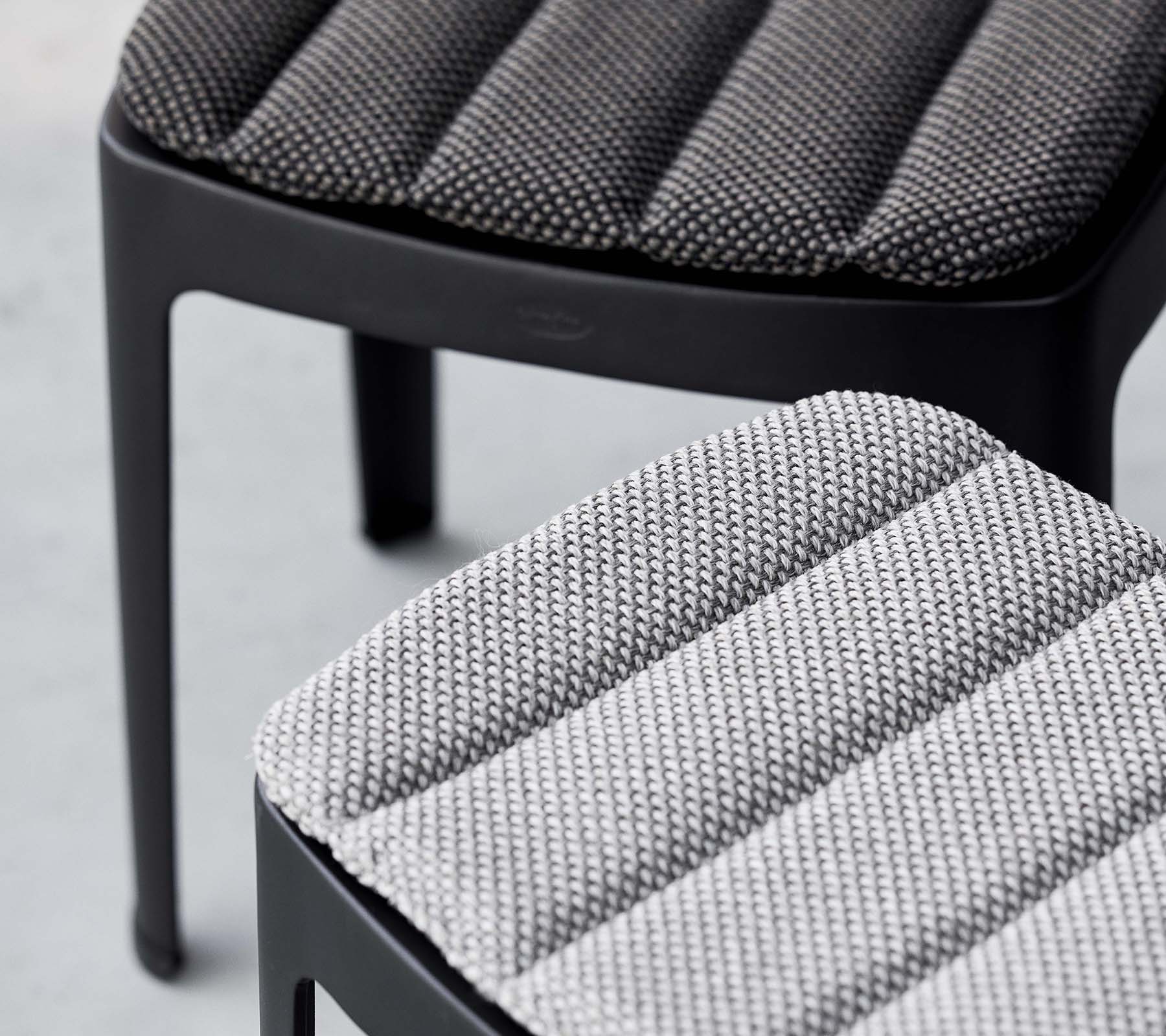 Dos taburetes elegantes con tapicería texturizada en tonos de gris contrastantes, que muestran un diseño moderno con líneas elegantes.