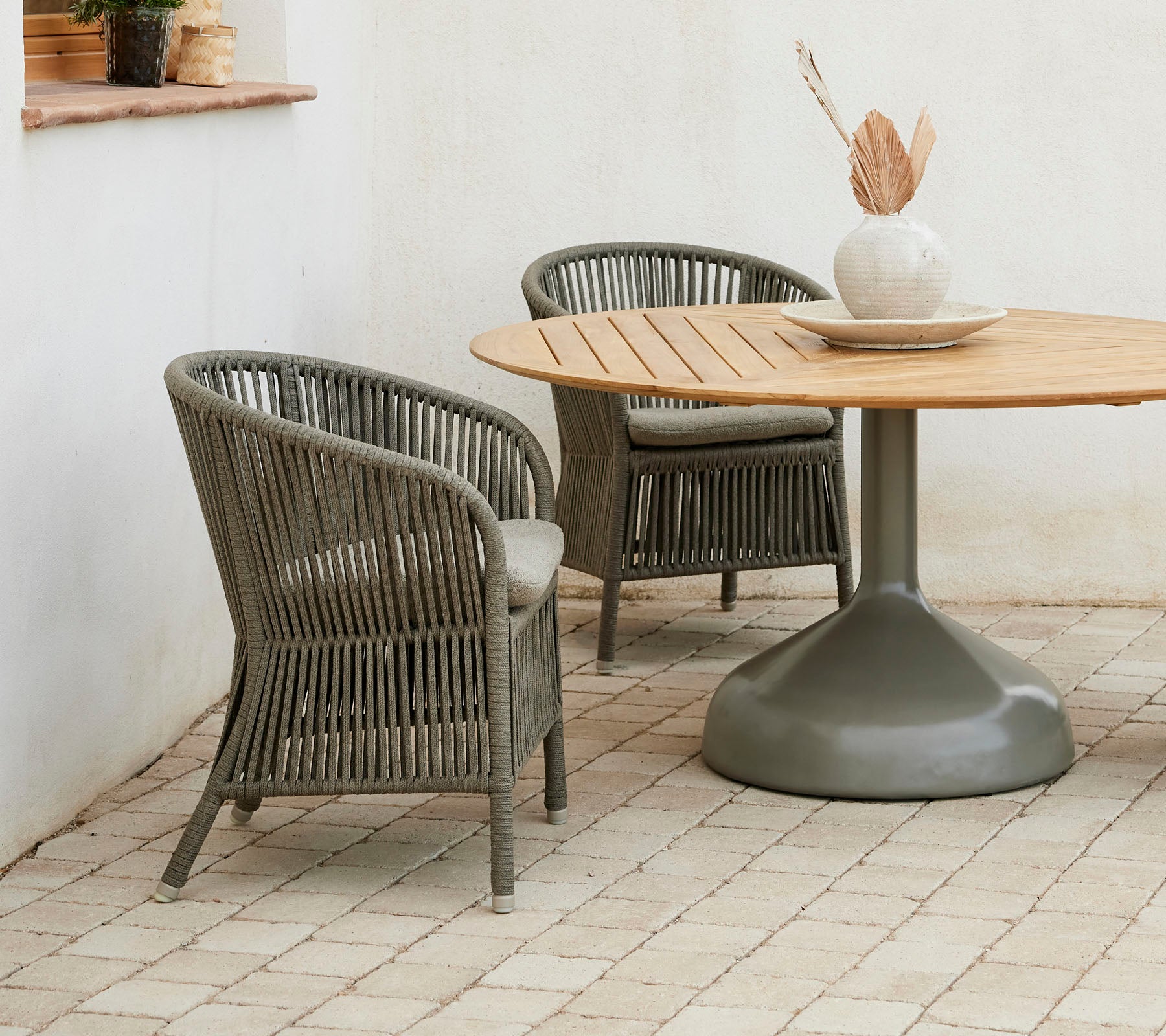 Dos elegantes sillas Derby junto con una mesa de comedor redonda Glaze, que presenta una paleta de colores neutros y un jarrón decorativo.
