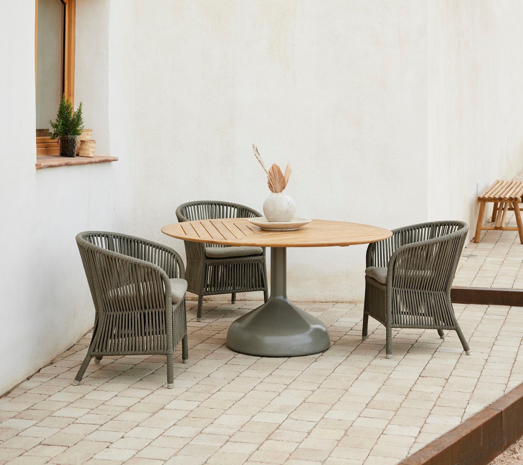 Una elegante configuración de comedor con una mesa redonda de madera rodeada de sillas Derby elegantes, creando una atmósfera acogedora.