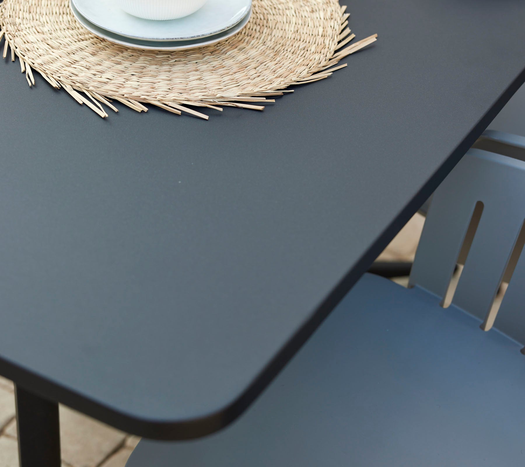 Una mesa de café moderna con una superficie suave, acompañada de un mantelito redondo decorativo y una taza en una silla acogedora.