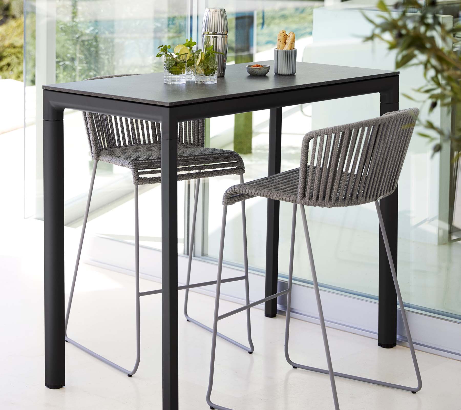 Mesa moderna con dos taburetes elegantes, con un diseño elegante, acompañada de plantas decorativas y accesorios de comedor minimalistas.