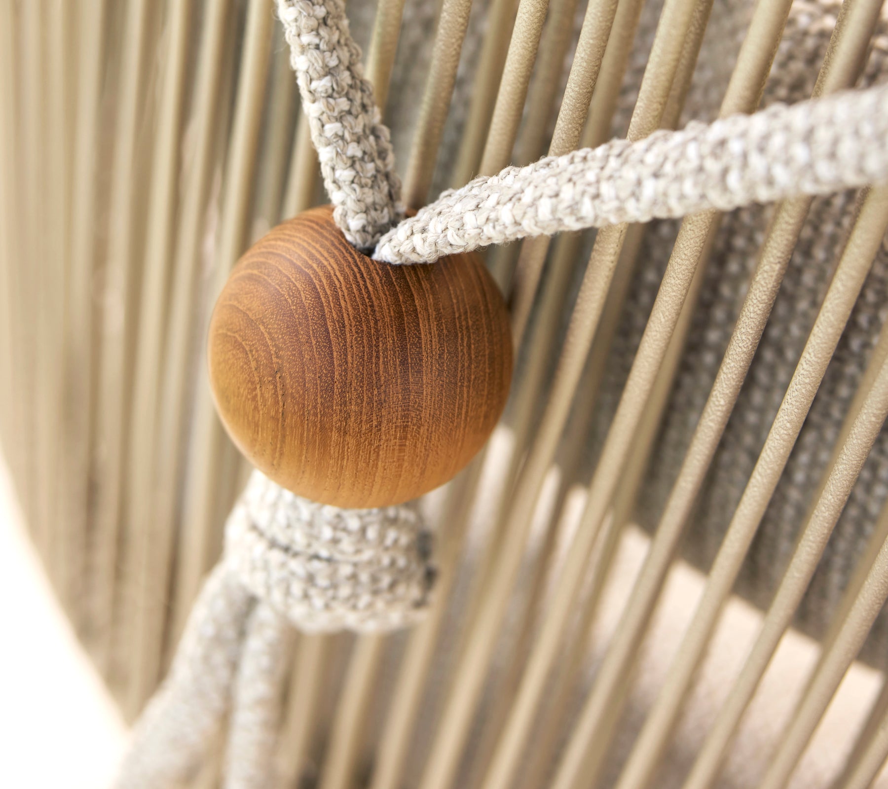 Primer plano de un soporte para cojín de cuello para una silla Hive, que presenta una perla de madera y correas de tela tejidas.