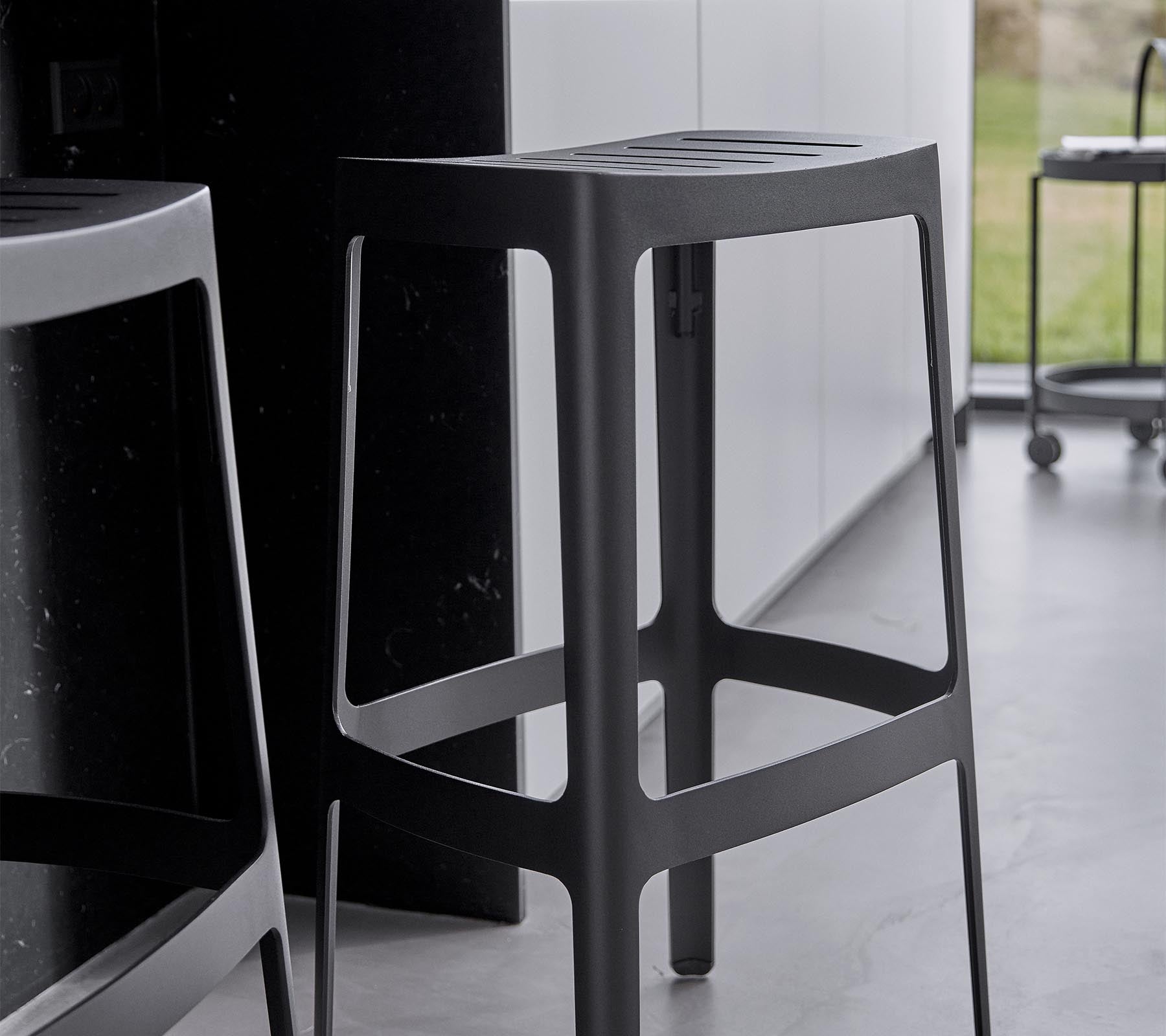 Un taburete de bar elegante y moderno con un diseño minimalista, que presenta una estructura resistente y un elegante acabado negro.