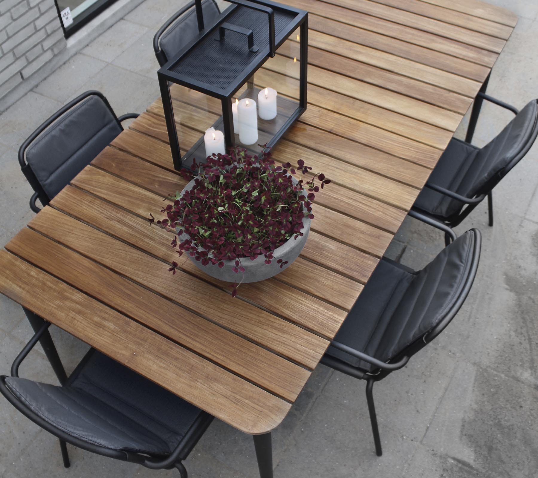 Una mesa de madera con sillas negras, con un gran macetero y un candelabro como centro.