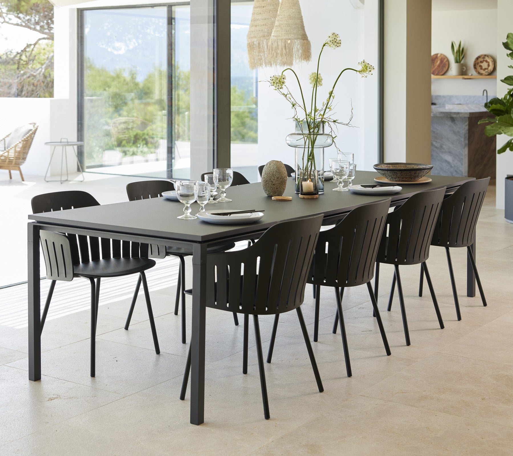 Un elegante juego de mesa de comedor con ocho sillas negras, dispuestas de manera elegante con vajilla y un jarrón de flores como punto focal.