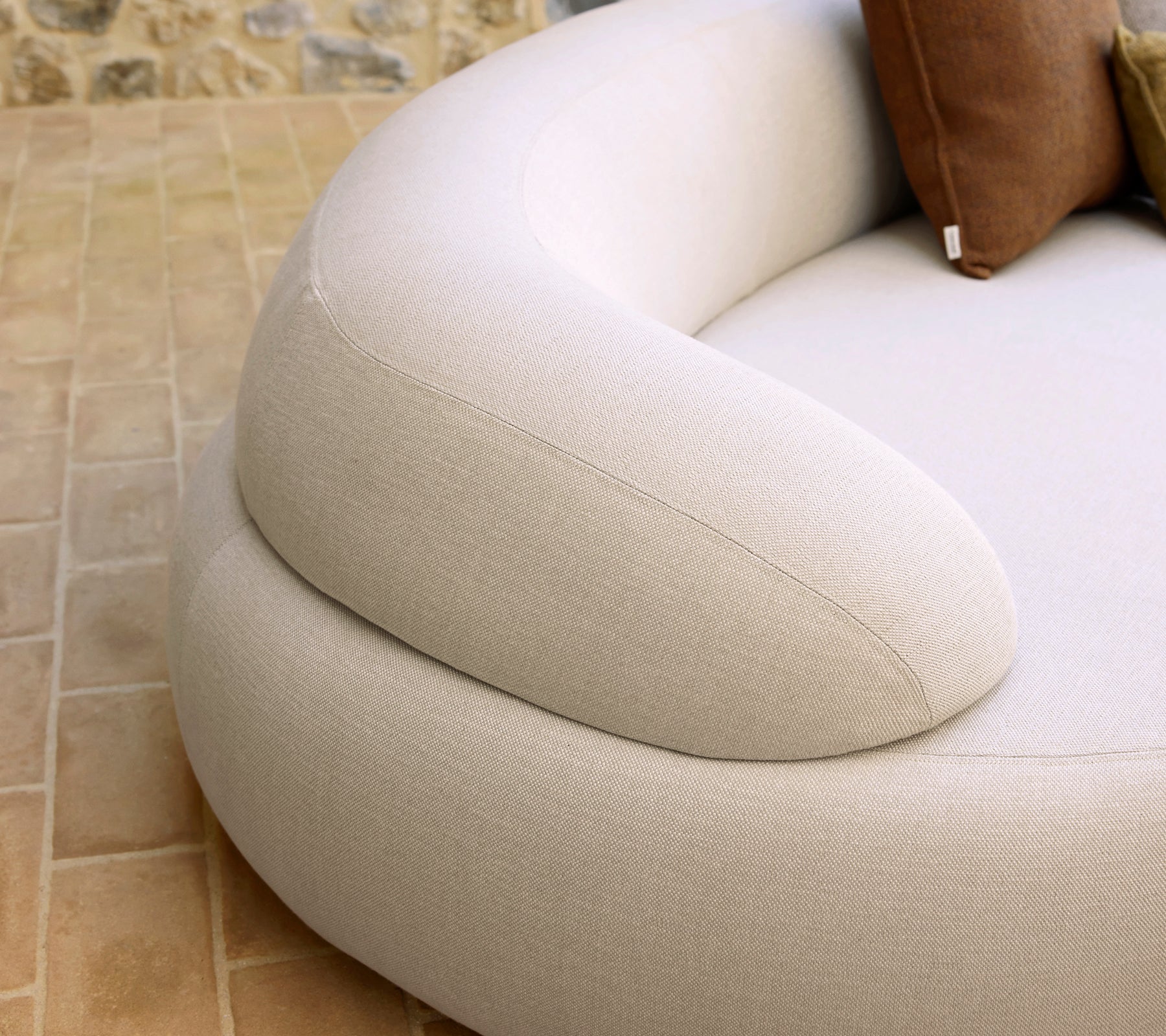 Descansabrazos suaves y redondeados de una pieza de asiento acogedora, con una tela ligera y cojines decorativos a juego.