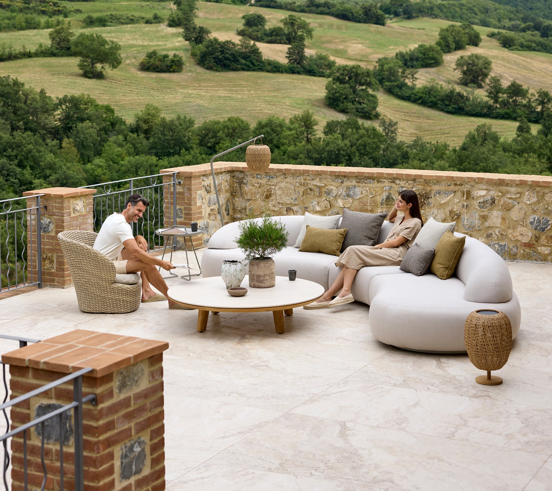 Arreglo de asientos relajantes con un suave sofá lounge, silla Coast, mesa de café Aspect y acentos Illusion Glow con un fondo escénico.