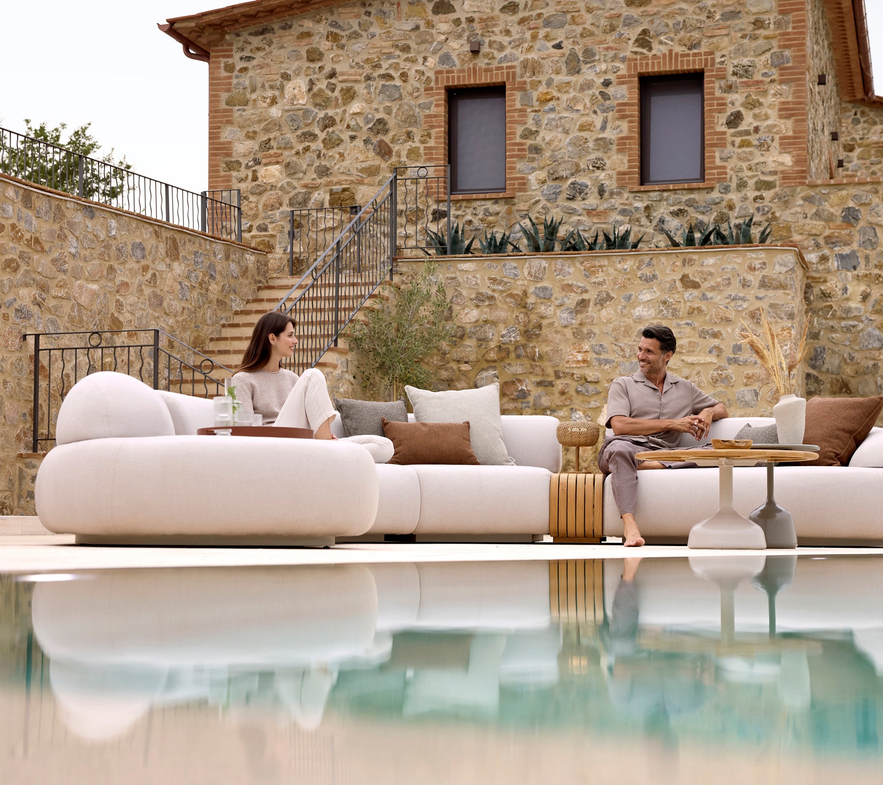 Dos personas se relajan en un suave sofá lounge, combinado con una mesa de café Glaze y una mesa de café suave, que refleja una atmósfera serena.