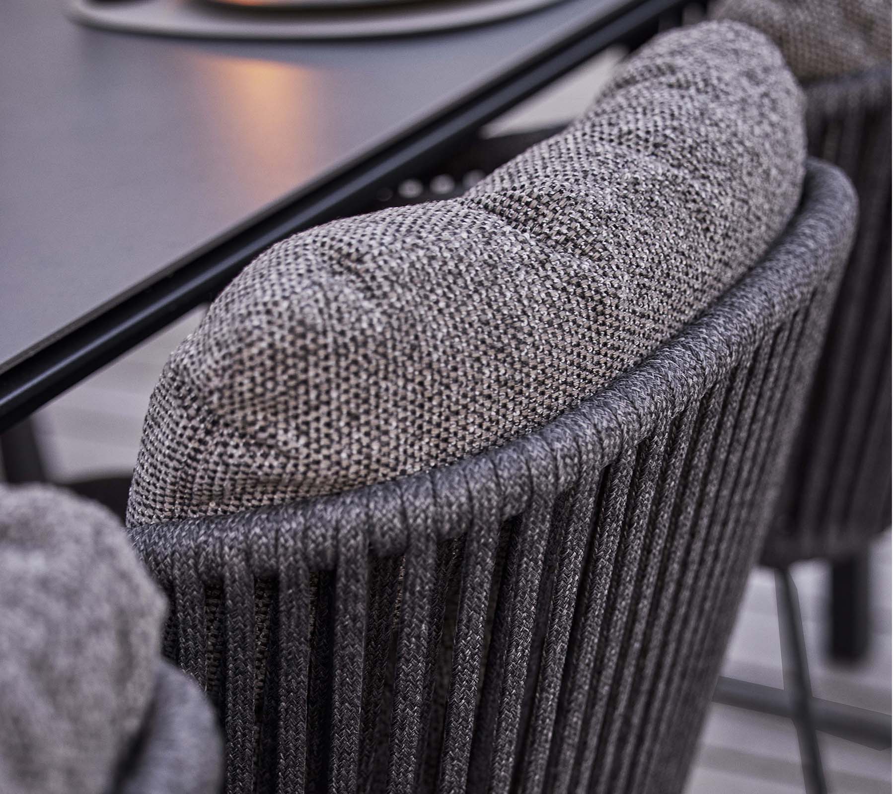 Primer plano de un respaldo de silla texturizado con un cojín suave y acolchado, que presenta un diseño estriado vertical elegante.