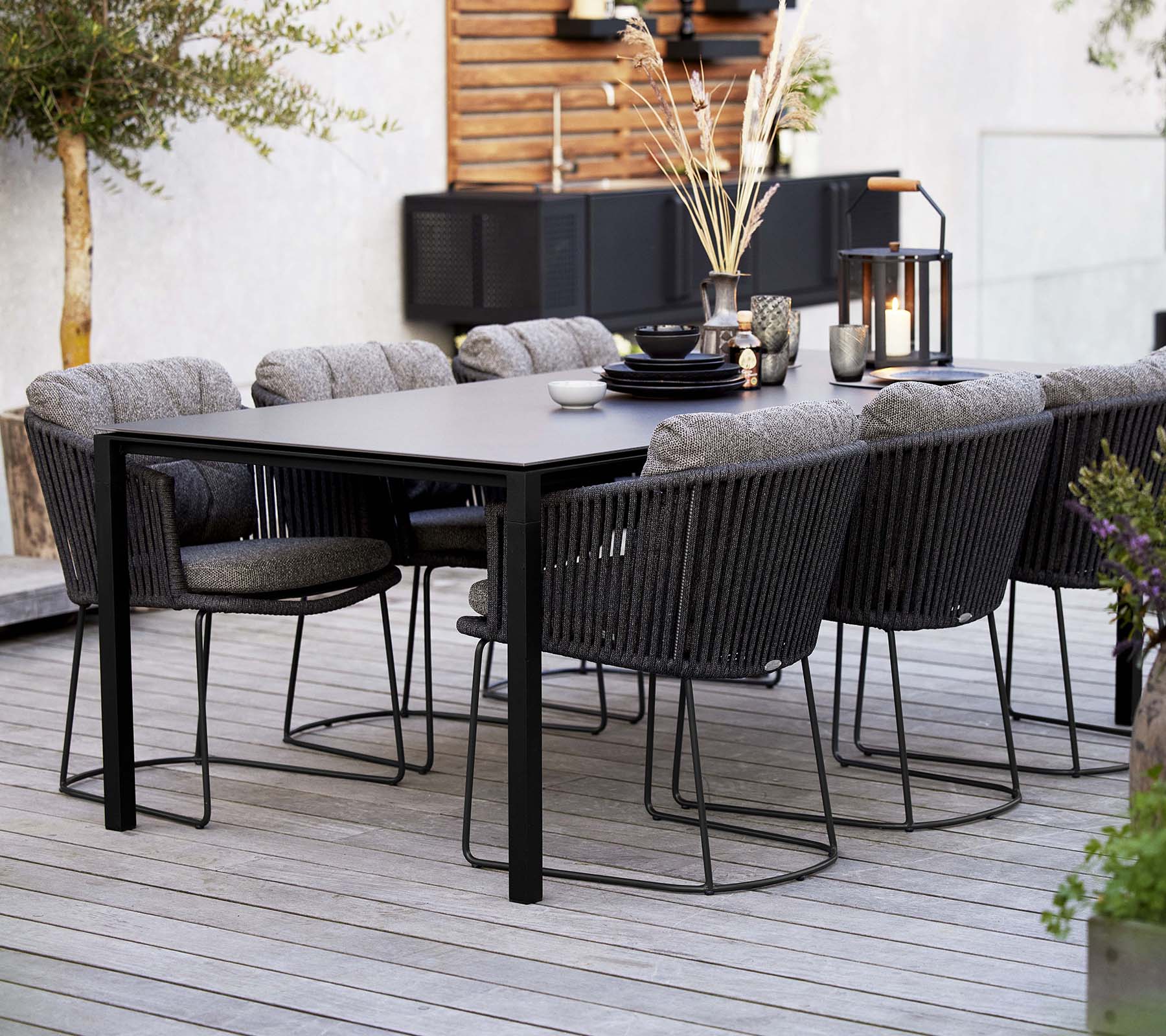 Una elegante disposición del comedor con una mesa elegante rodeada de cómodas sillas trenzadas, adornada con elementos decorativos y plantas.