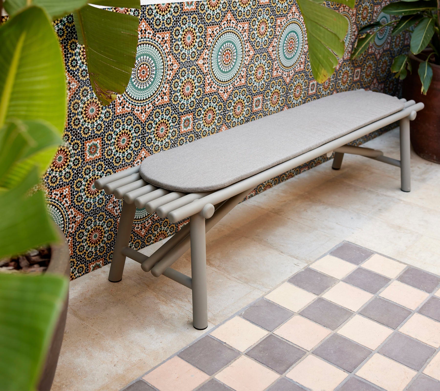 Un banco elegante con elementos de diseño en forma de palo, complementado con un fondo de patrones geométricos y una vegetación vibrante.