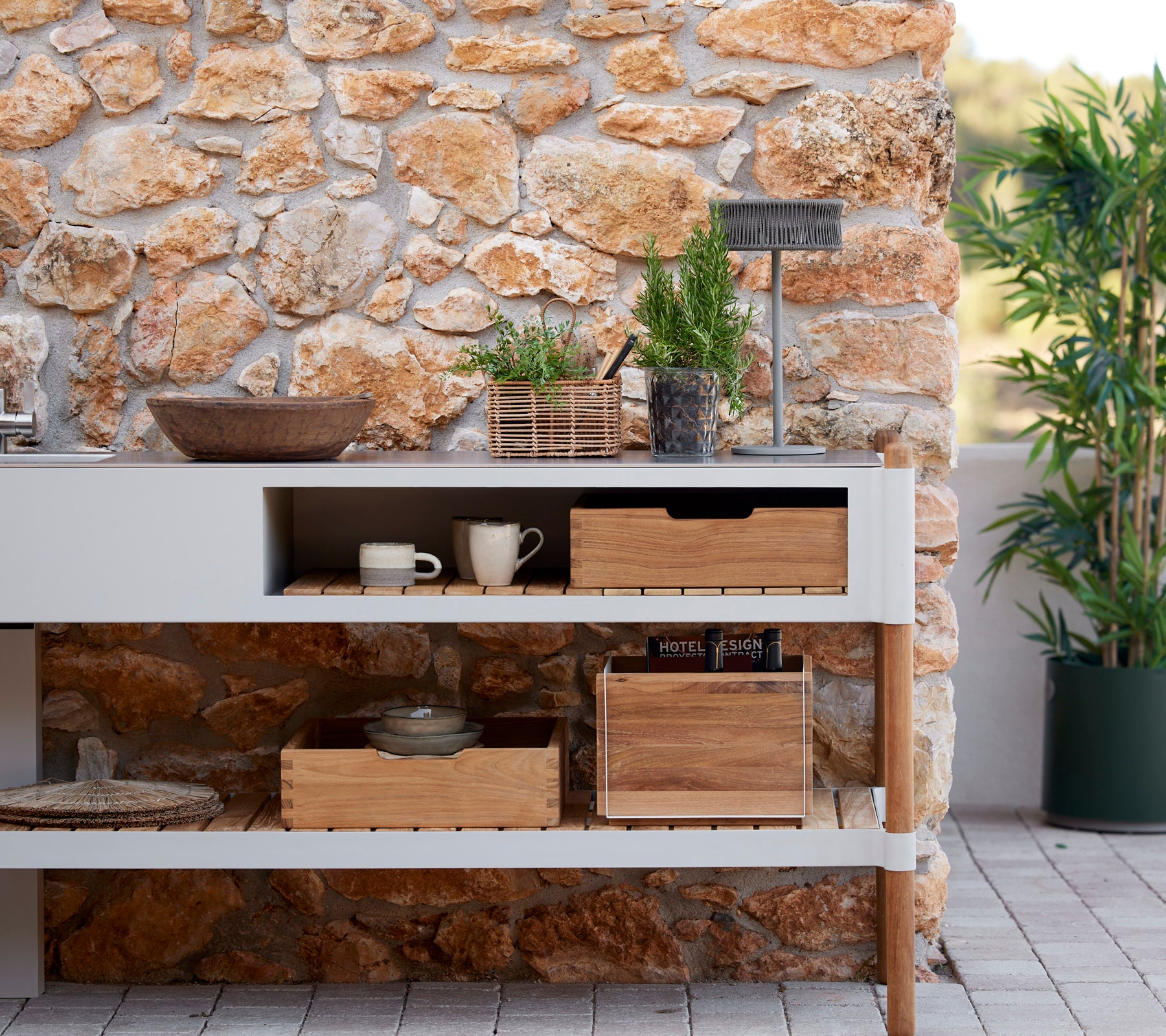 Configuración de cocina elegante con una pared de piedra, cajas de almacenamiento de madera, plantas en macetas y una lámpara de ilusión para una atmósfera acogedora.