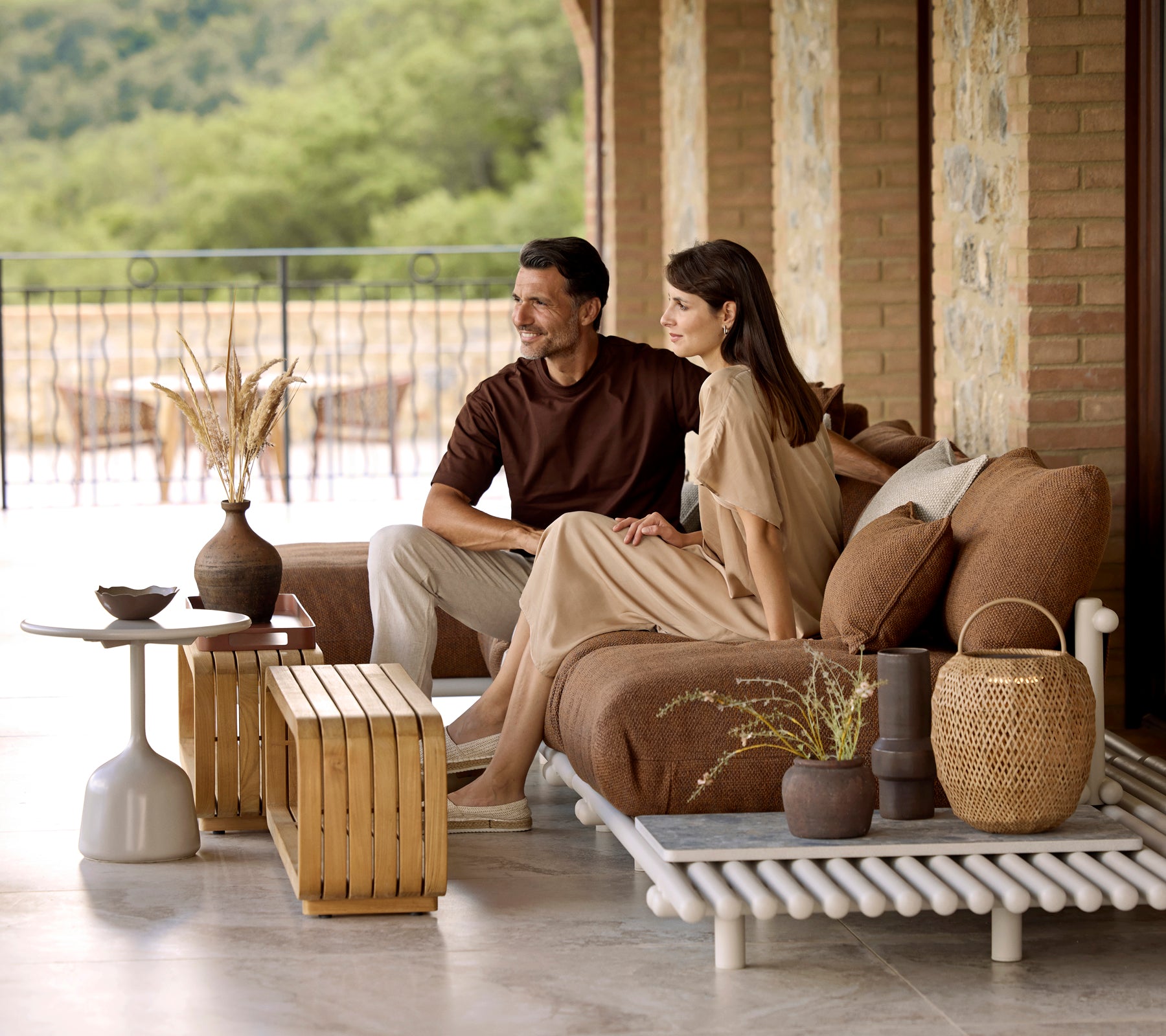Una pareja está sentada juntos en un sofá elegante, rodeados de elementos decorativos que incluyen una mesa de café suave y acentos de buen gusto.
