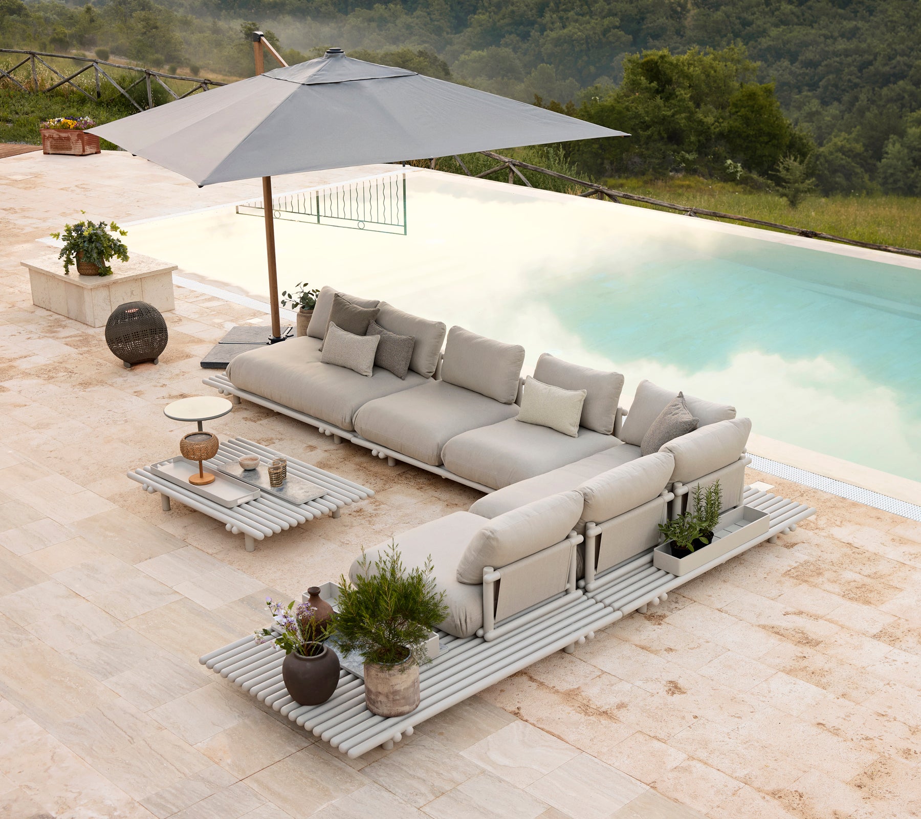 Conjunto de salón de aluminio elegante con cojines suaves y una mesa de café a juego, complementado con un paraguas y plantas decorativas.