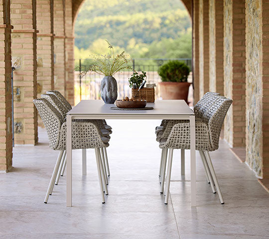 Una elegante disposición de comedor con sillas Vibe y una mesa de comedor Pure en un suave color arena, con elementos decorativos.