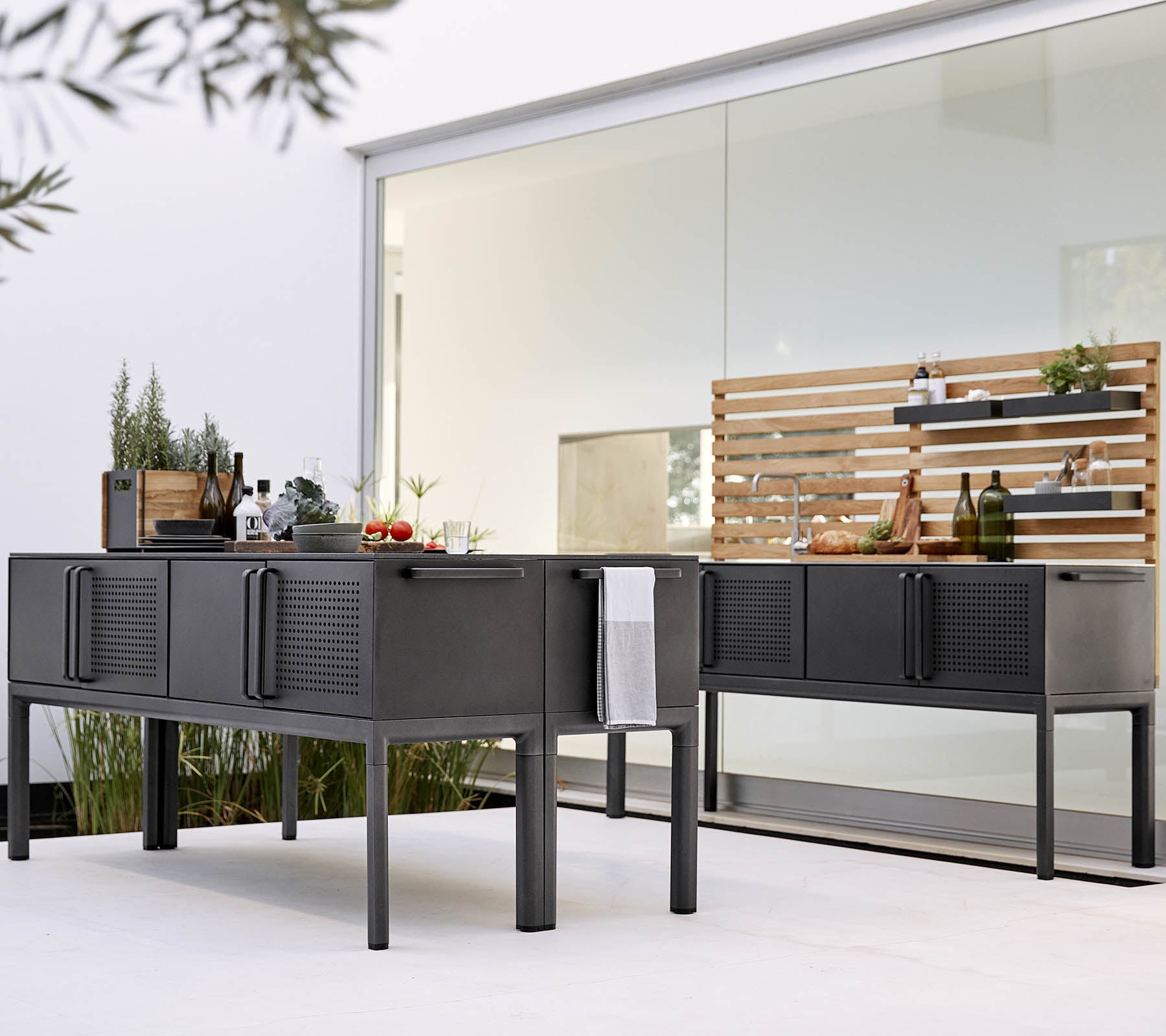 Configuración contemporánea de cocina al aire libre con elegantes gabinetes negros y una estantería de madera para almacenamiento y exhibición.