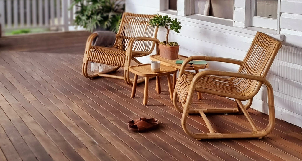 Two lounge chairs with small teak side table on a veranda