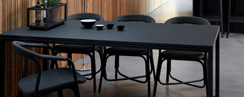 Mesa de comedor negra moderna acompañada de sillas elegantes, con elementos decorativos en la superficie de la mesa.