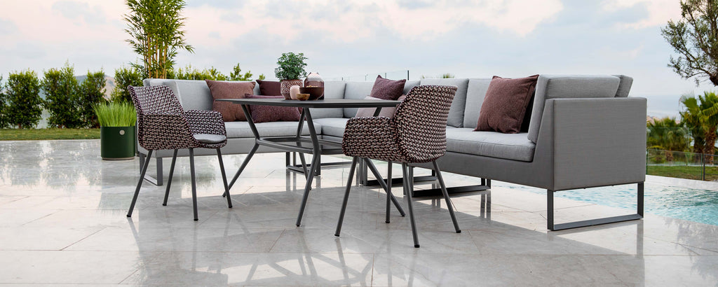 A modern seating arrangement featuring a gray sofa with plush cushions, a stylish table, and matching chairs, perfect for relaxing and dining.