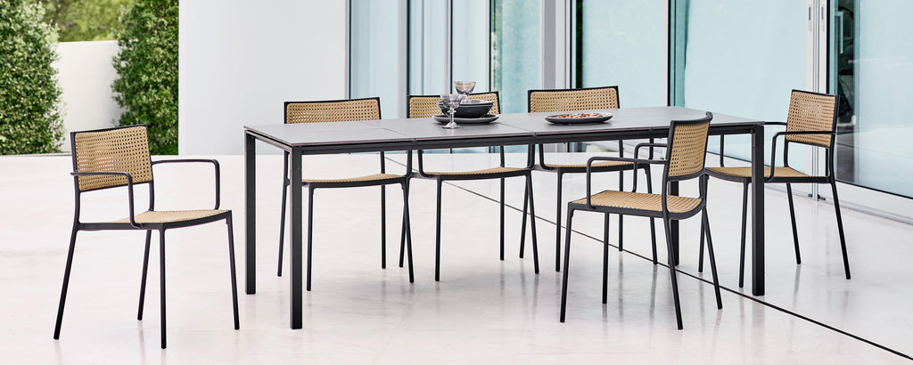 Modern table with six chairs featuring a sleek design and a combination of metal and woven elements, complemented by decorative centerpieces.