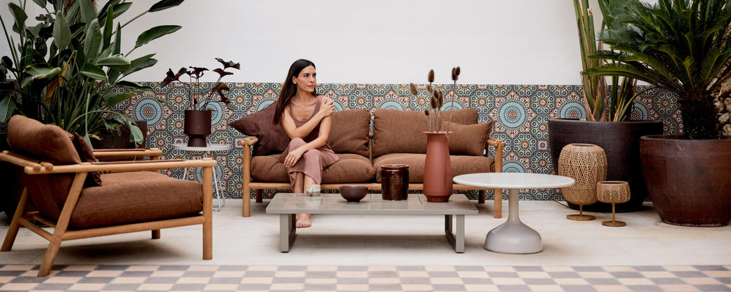 A stylish lounge area featuring a comfortable sofa, modern coffee table, decorative vases, and lush greenery for an inviting ambiance.