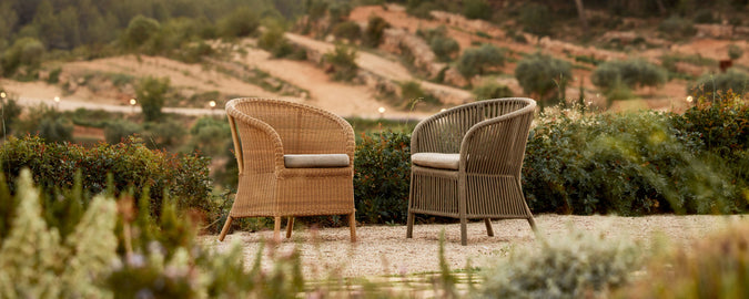 Two stylish wicker chairs with cushions positioned in a scenic landscape, inviting relaxation and conversation.
