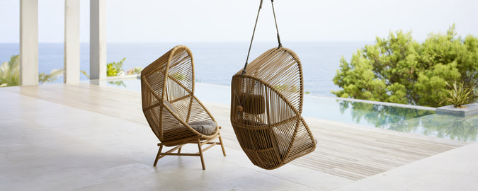 Dos sillas colgantes modernas en un entorno contemporáneo con vistas al agua.