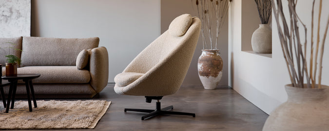 Silla giratoria beige y sofá gris en un ambiente moderno.